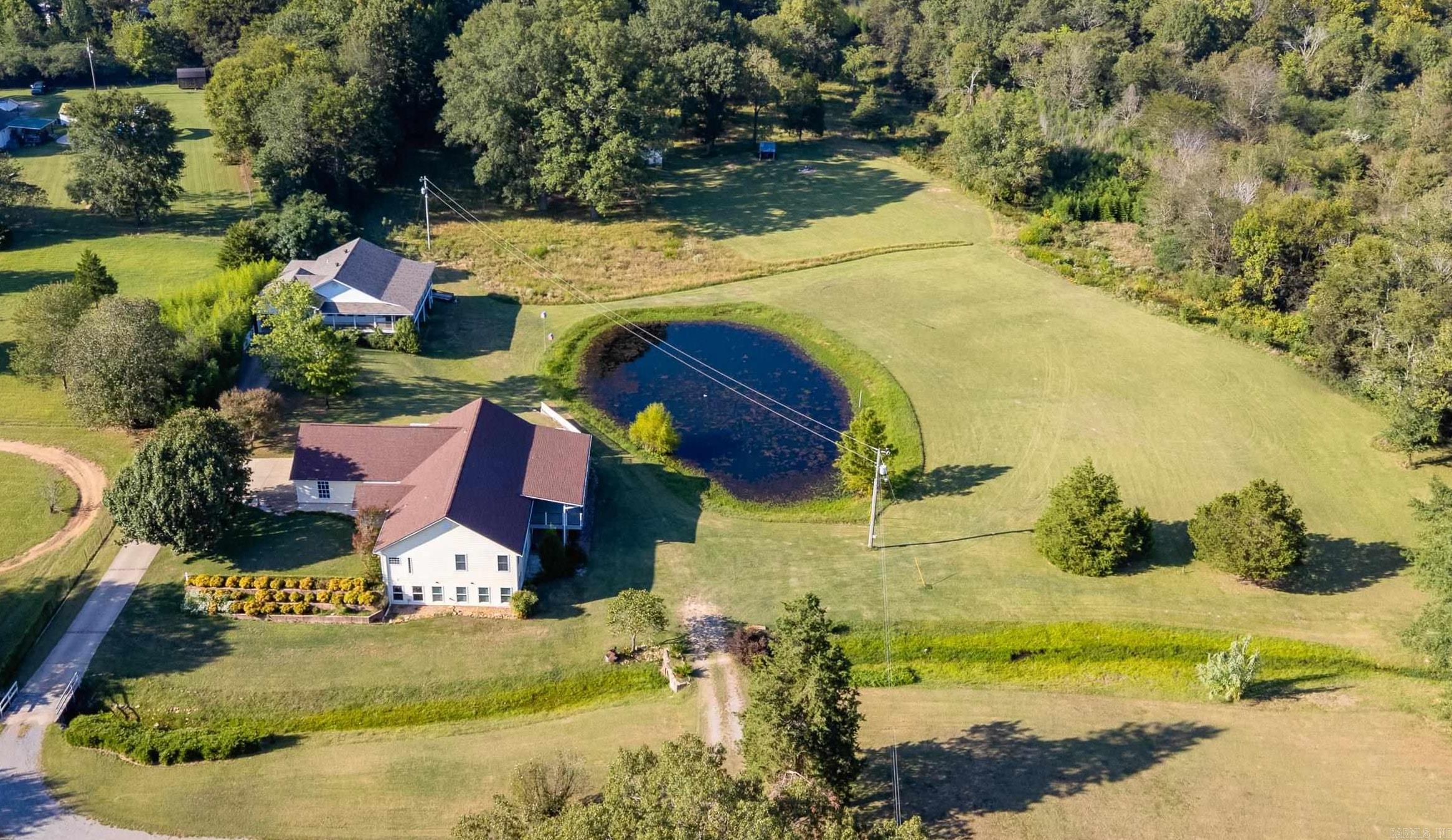 Spacious Home with Acreage, Pond, and Guest House. Discover the perfect balance of comfort and country living with this unique property just outside city limits. Set on 11 serene acres with a private pond and chicken coops, this 2-story home offers plenty of space both indoors and out. The main residence features 5 bedrooms & flexible living with kitchens on both the main & lower levels—ideal for entertaining, multi-generational living, or hosting guests. A large, covered porch invites you to relax and enjoy the peaceful views. Recent updates include newer roofs and HVAC systems. Both levels offer handicap accessible bathrooms. In addition to the main home, a separate detached residence with over 1,300 sq ft, 2 beds/lg deck, provides endless possibilities: guest quarters, rental income, or a private office space. Handicap accessible. Located just minutes from highly rated schools, Walmart, and only 22 minutes from the West Little Rock Costco, you’ll enjoy the conveniences of town while embracing the beauty of a rural setting. This property is a rare find—spacious, versatile, and designed for those who value both community and privacy. Agents, pls see list of updates & remarks.