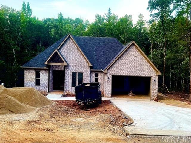 Brand new 1885 square foot home on lovely lot. Trees surround this lovely home with no homes behind. Spacious open floor plan gives you a perfect entertaining area with living, dining and kitchen all connected. You will not be isolated in the kitchen while the family enjoys visiting. Kitchen features a large island and large pantry for your convenience. White cabinetry and counters are an elegant white quartz. Living room opens to a concrete deck perfect for outdoor Village living. Primary bedroom with walk in closet and bath with soaking tub and separate shower. Living area and all bedrooms have a very nice neutral LVP for easy living and low upkeep. Baths feature tile flooring and tub. Three additional bedrooms complete this modern floor plan. Fourth bedroom would make an excellent office or computer room. Taxes are based on vacant lot. Interior pictures are of recent homes completed by builder. Hot Springs Village boasts 9 golf courses, 11 lakes, pickleball, hiking trails, white sand beach, tennis, fitness center and much more. HSV has one time $2000 buy in for new residents.