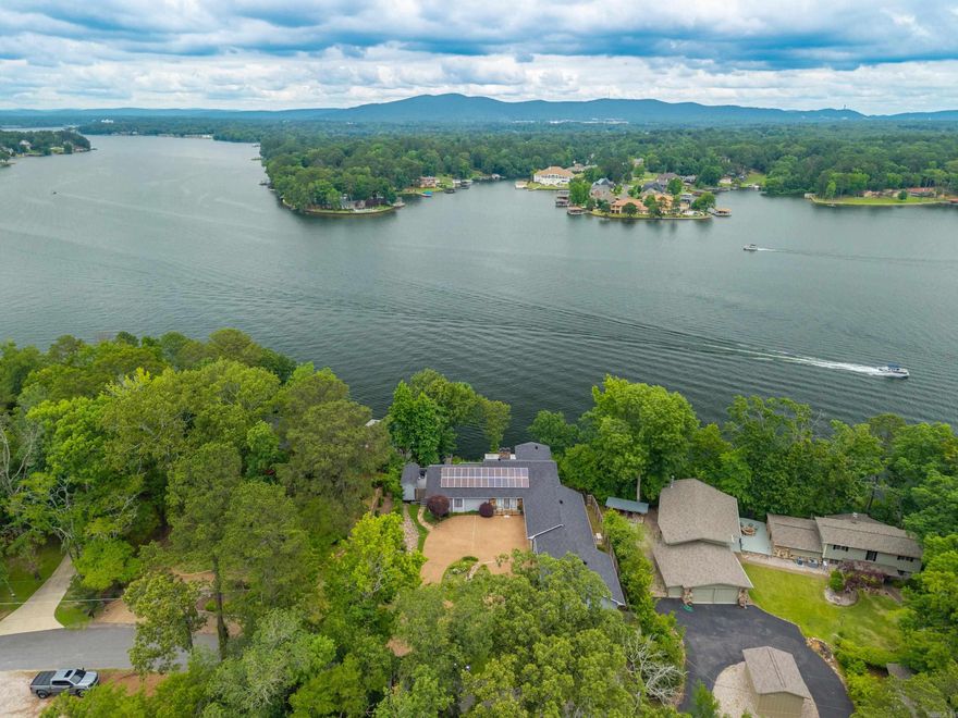 Welcome to 139 Sammie Cove in the prestigious Tanglewood Subdivision on beautiful Lake Hamilton—an exceptional income-producing lakefront retreat offering sweeping main-channel views and over 4,000 square feet of combined living space. This expansive property features a grand two-story, 3,480 SF primary residence plus a 634 SF attached guest cottage with private entrance and full functionality, ideal for extended family, guests, or additional rental income. Designed to capture panoramic water vistas from nearly every angle, the home blends contemporary and traditional architectural elements with light-filled interiors and generous gathering spaces. The primary residence offers multiple living and entertaining areas, all positioned to maximize the stunning lake views. Large windows invite natural light throughout, while shared living spaces and bedrooms enjoy picturesque water perspectives. A charming three-season room provides the perfect setting for morning coffee or evening relaxation, and two spacious decks offer ample room for outdoor dining, entertaining, and soaking in the scenery.