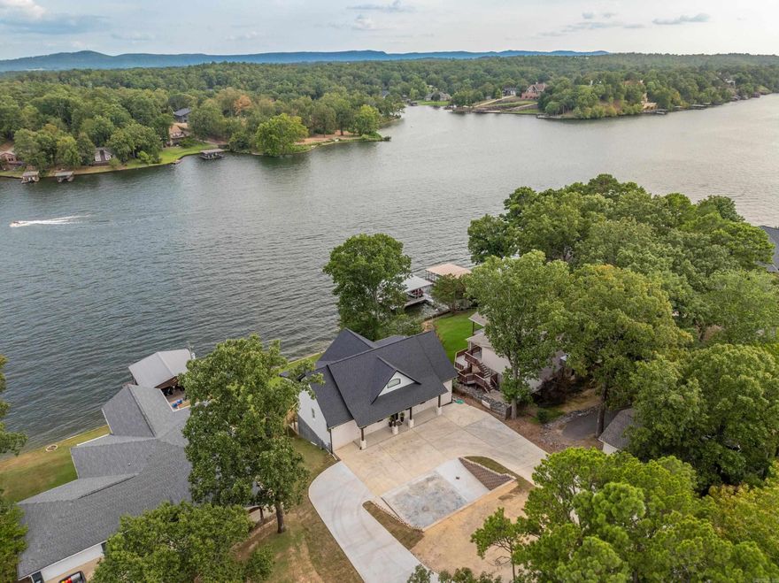 Elegance and Style Await You on the MAIN CHANNEL of Lake Hamilton. Designed with comfort and ease of use in mind, this two-story home offers 5 bedrooms, including bunkroom, and features en suite bathrooms for each.  Three bedrooms provide stunning main channel views and the primary suite provides direct deck access.  A bonus/flex room with wet bar serves as the ideal second living space or game room.  Soaring ceiling on both levels create a spacious, open feel, complimented by top-quality craftsmanship throughout.  The kitchen is a showstopper featuring stainless steel appliances, double wall ovens, dual dishwashers and luxurious leathered granite countertops.  A mechanical room with an additional closet provides extra storage space.  Whether you’re seeking a full-time residence or lakeside getaway, this home offers the perfect blend of luxury, functionality and stunning waterfront views.  Located outside the city limits, allowing for short-term rentals without a permit.