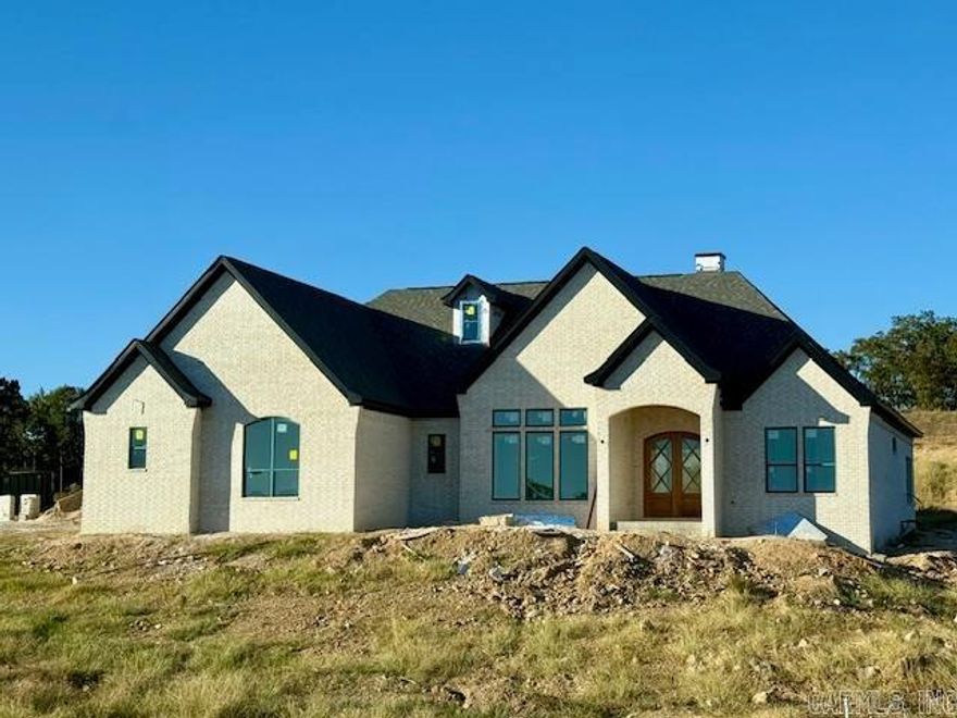 LAKE HAMILTON VIEWS ABOUND IN THIS NEW CONSTRUCTION HOME IN GATED COMMUNITY JUST MINUTES FROM OAKLAWN! Step inside to soaring spaces filled with natural light, an inviting living room with built-ins and a gas fireplace, and an open kitchen featuring a quartz island, breakfast bar, huge walk-in pantry, and expansive dining area. The primary suite is a showstopper with cathedral ceiling, spa-worthy freestanding tub, custom tile shower, and a massive walk-in closet that connects to the laundry room. A stunning office with 12-foot ceilings, French doors, and incredible lake views makes working from home a dream. Upstairs offers a versatile bonus room or bedroom with full bath and private balcony overlooking the water. Enjoy outdoor living with a covered porch and outdoor kitchen, plus a 3-car garage, mudroom, and private neighborhood boat launch—all with hardwood floors, designer lighting, and top-tier finishes throughout. Estimated completion October 2025, still time to pick some finishes!