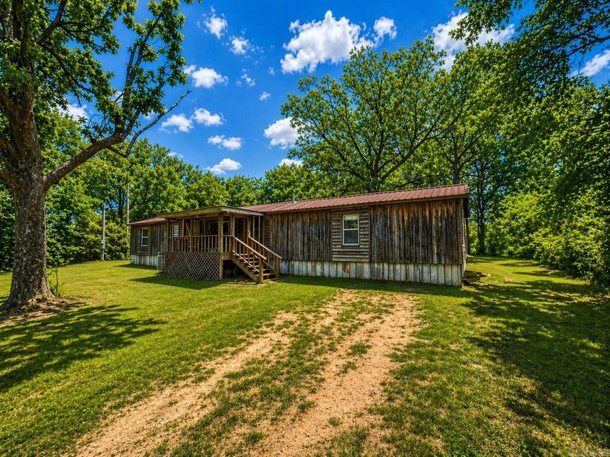 Nestled in the beautiful Ouachita Mountains of Story, Arkansas, this one-acre property offers a peaceful setting just under 20 minutes from the beautiful waters of Lake Ouachita. The land includes a working well, septic system, storage building, front covered porch, and open back deck. Conveying with the property is a 1,594 sq. ft. single-wide mobile home offering 3 bedrooms, 2 baths, and a fixer-upper opportunity ready for your personal touch. Your ideal mountain retreat awaits!  *AI was used on listing photos to remove livable clutter and enhance lighting. No changes to the structure or conditions were made.