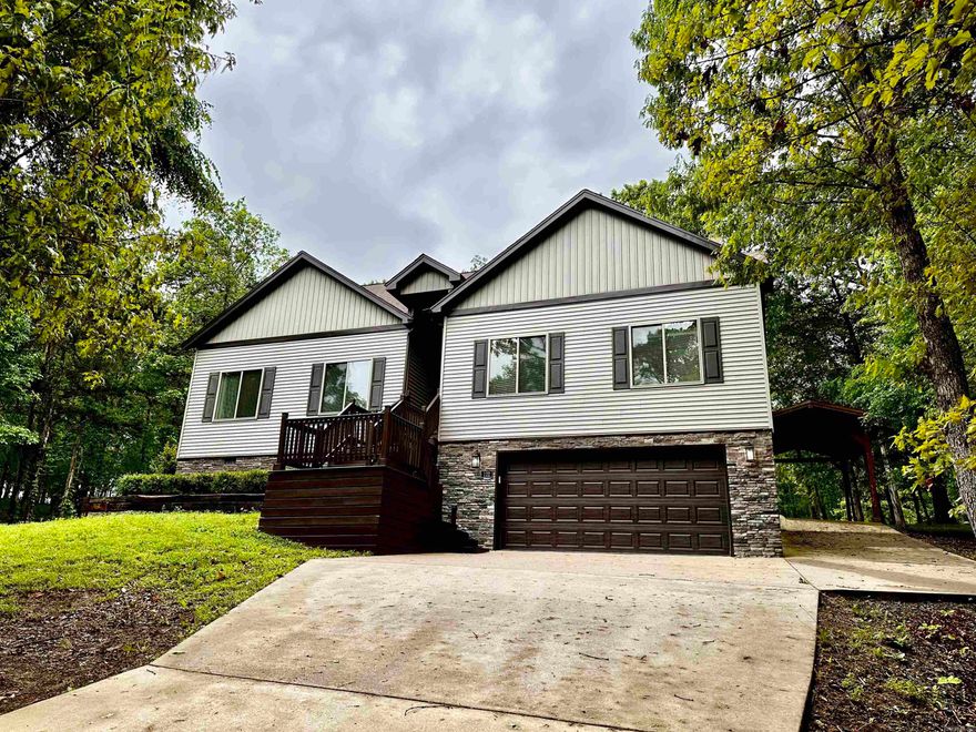 Welcome to 122 Crest Drive, Fairfield Bay, AR, a beautifully designed single-family residence nestled in the heart of Fairfield Bay. This property boasts 4 spacious bedrooms, a media room, 2 modern bathrooms and an expansive 2120 sq. ft. of living space, offering a perfectly blend of comfort and luxury. Open concept living, the seamless integration of the kitchen, dining, and living areas creates an inviting space for gatherings and daily living. The gourmet kitchen has granite countertops and ample cabinets, a large pantry and stainless appliances. The media room offers a dedicated space for movie nights or gaming sessions. The home also features an on-demand circulating hot water system. The double garage is located below the house, along with a large storage area, a separate carport has been added to the side of the home, off of the deck. Home is situated on the Indian Hills Golf Course on the 3rd hole. A large deck covers the back of the home so you can enjoy serene views and peaceful family gatherings. The property also includes a smart irrigation system. Lot to the south of property has been replatted and will convey with the property.