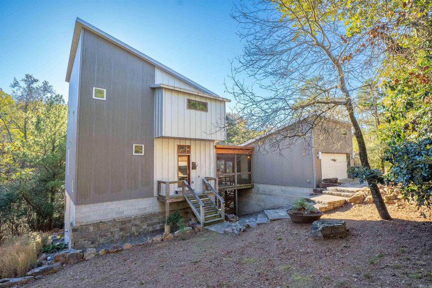 Exceptional contemporary home in highly sought-after Woodglen! This one-of-a-kind property is set on a private, wooded .84-acre lot backing to Jimerson Creek, offering a rare blend of modern design and natural serenity. Inside, you'll find a warm yet sophisticated living space featuring walnut floors, abundant natural light, and picturesque views through expansive windows. The screened porch overlooks a peaceful stone patio with fire pit, perfect for outdoor relaxation and entertaining. Upstairs, the primary suite offers a private retreat with its own balcony, a spacious spa-like bathroom, and a generous walk-in closet. Downstairs includes a large flex bedroom with potential to be partitioned into an additional bedroom or office. This versatile space features two garage-style doors that open to a second screened porch, seamlessly blending indoor and outdoor living.  Agents: see remarks for additional details.