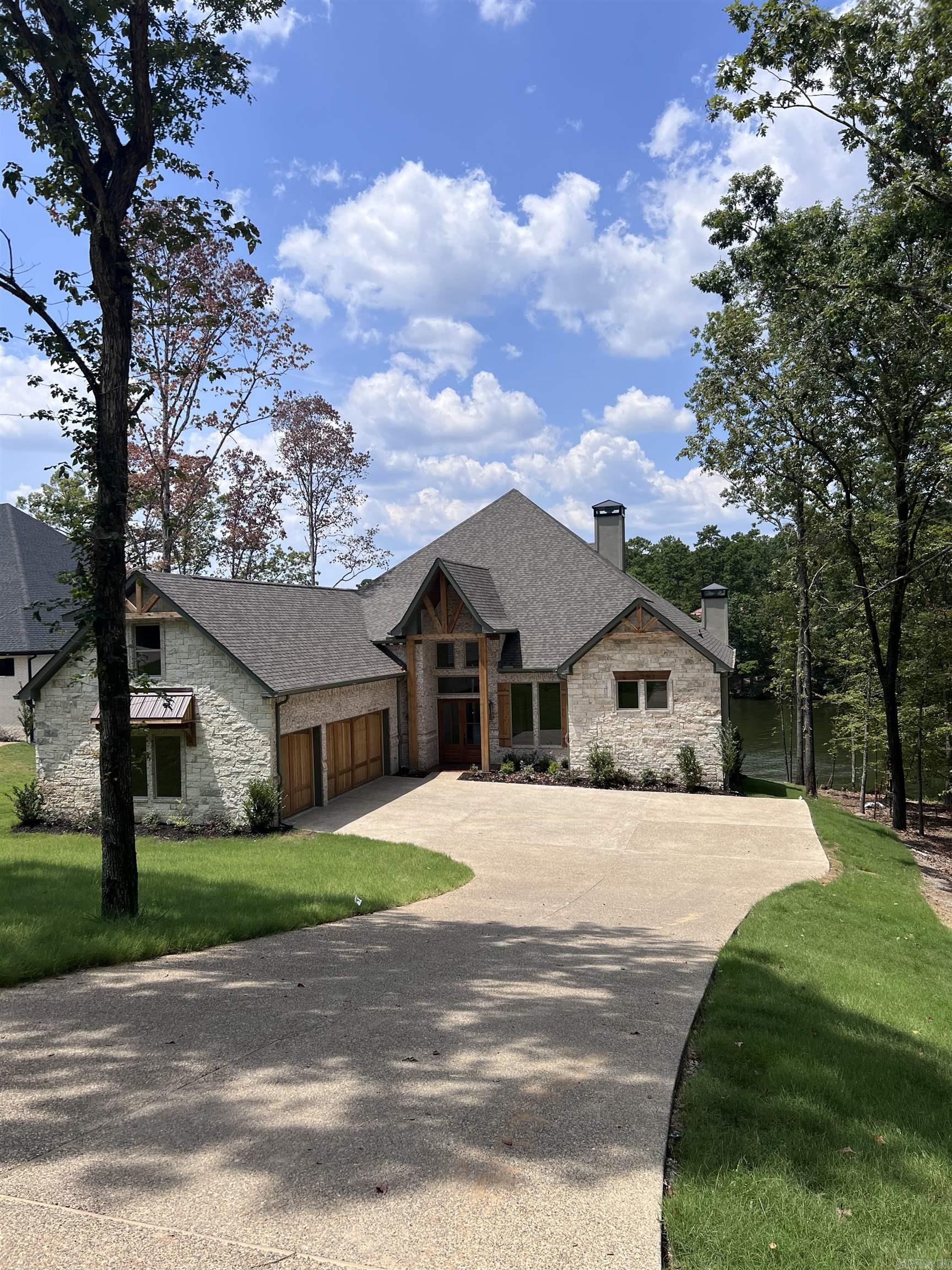 This home checks all the boxes: New Construction on Lake Hamilton, Deep Water and Expansive views, Highly Desired 7 South location and a Stunning Home with the appointments you are looking for. Beautiful wood ceilings and beams add charm to this open floorplan home that welcomes your family and guests. Large granite island in the chef’s kitchen, with custom cabinets throughout. Three fireplaces add to the warmth and coziness of this lakeside retreat. The primary bedroom features a vaulted wood ceiling, fireplace, and private coffee bar. Custom His and Her closets with plenty of storage and built ins. The primary ensuite has a luxurious Roman Double Shower and his and hers vanities and a soaking tub. All bedrooms in the home are ensuite. The outdoor living area is covered and has a fantastic outdoor kitchen. This home has a boat dock permit that will transfer at closing. POA is currently being formed, no financial or dues amount have been established but developer had indicated it should be like Blue Herron POA. Estimated completion Spring 2024.