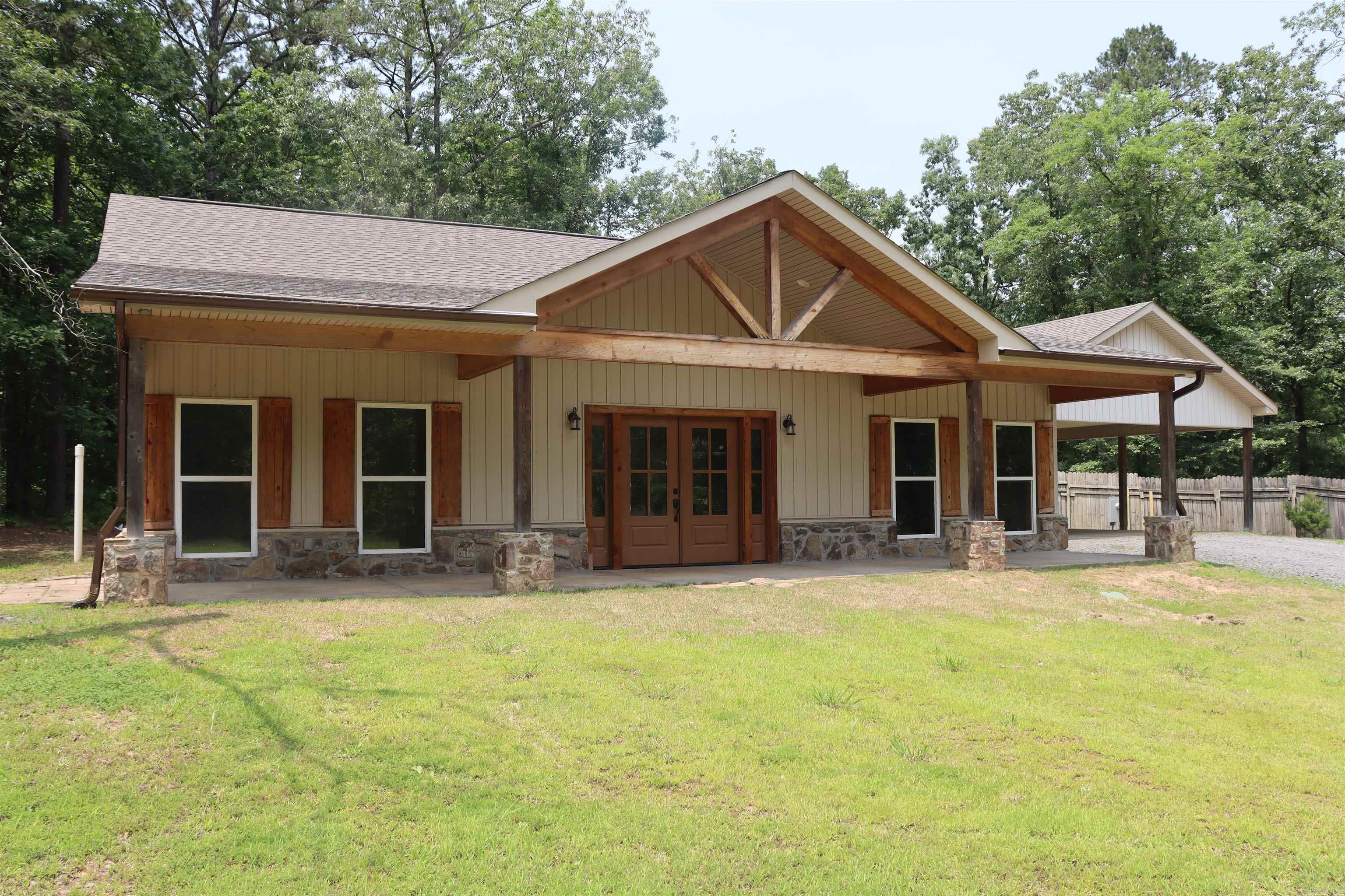 Take a drive down your own long, private driveway and arrive at a cozy, 2022-built retreat tucked into 2 wooded acres. Step onto the welcoming front porch—perfect for your morning coffee—and through double front doors that open to pine walls, ceilings, and stained concrete floors throughout. Look up and admire the stunning exposed beam and vaulted ceiling in the open living space. Picture yourself curled up by the wood-burning stove in a rock fireplace on chilly nights. The kitchen is equipped with appliances just 2 years old, and both bathrooms feature beautiful walk-in tile showers with seating. The primary suite's double-head shower brings spa vibes home. Step back outside to peaceful summer evenings on the porch. Just minutes away? Lacey Marina and Greers Ferry Lake—ready for boating, kayaking, or relaxing lake days. A covered two-car carport has room for your ATV or side-by-side. This isn’t just a home—it’s a lifestyle. Come see it for yourself.
