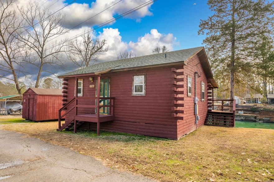 Escape to tranquility in this charming, small log cabin nestled along the shores of Lake Hamilton. Embrace the simplicity and warmth of this one-bedroom, one-bathroom retreat, where every detail is designed to create a cozy and inviting atmosphere. The heart of the cabin features a corner gas log fireplace, adding a touch of rustic charm and loft providing additional space for storage. Step outside onto the covered back deck to enjoy breathtaking views of the lake, creating an idyllic setting for morning coffee or evening sunsets. Boating enthusiasts will appreciate the convenience of the covered boat dock and boardwalk along the water's edge. For added functionality, the property includes a storage/workshop, providing a practical space for tools, outdoor equipment, or hobby pursuits. Whether you're seeking a weekend getaway or a year-round haven, this log cabin on Lake Hamilton is a serene retreat, offering a perfect blend of simplicity, natural beauty, and waterfront living. Immerse yourself in the tranquility of lake life and make this cozy cabin your own.