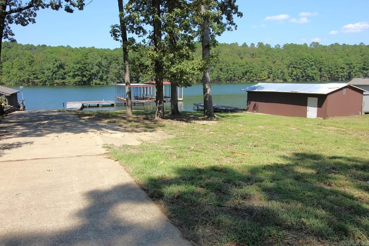 Lake lot on Lake Hamilton ready for your new home. .58 acre with 107 feet on the lake. Launching ramp, swim dock & two stall covered boat dock, concrete seawall all permitted. Most of the lot is above flood plain giving plenty of room for a home & gentle walk to the lake. City water meter & electrical meter pole in place. Pressure city sewer at the street. Located a short drive from Garvin Woodland Gardens. Survey on file. 16X35 ft. shop with roll up door that opens to a launching ramp into lake. 11X7 shop door. 8X32 pier adjacent to shop. 32 ft long pier out to 12X24 swim platform. Both boat stalls are 9'8" wide X 34 long X 9'6" high. Winter water with water depth in stalls at 9+ feet. Entergy permitting info on file.