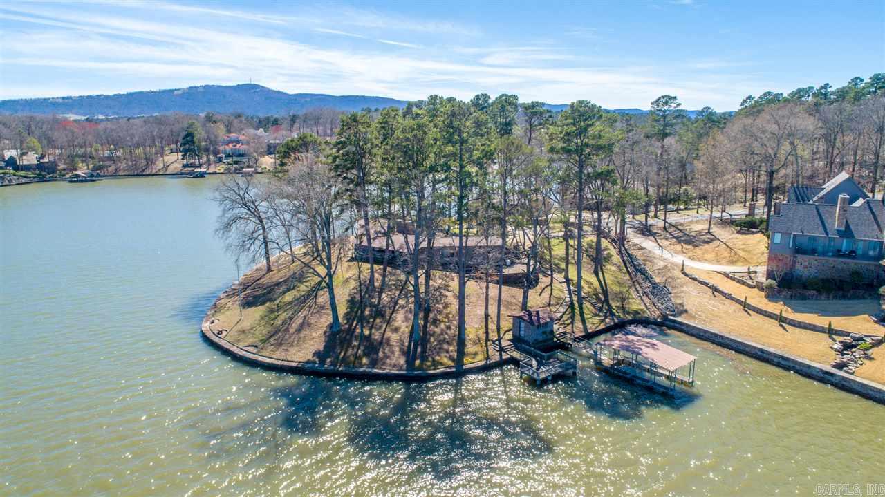 RARE OPPORTUNITY! Point on Lake Hamilton. Gorgeous main channel views from 3 sides with its 450 feet of lake frontage on 1.15 acres. Stroll the stone seawall path that traverses the full width of lakefront. Covered boat dock with adjacent deck for entertaining. While the value is mostly in the land, the 2105sf home is nestled in a serene, park-like setting, has lake views from every room. From here, it's an easy stroll to the lake down the stone paths. Much potential here! Situated just west of Kahuna Bay.