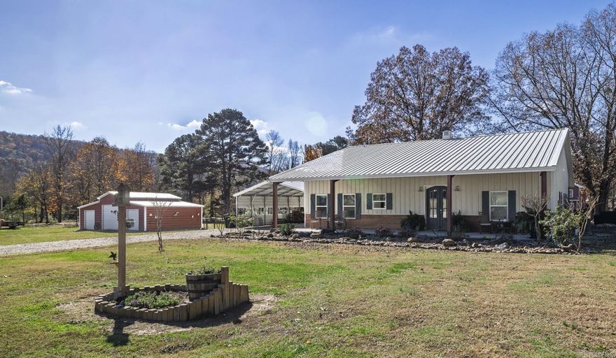 This charming 2000 sq ft home is situated on 3.3 level acres in a park-like setting with a shared pond and the Mountain Valley Creek which flows year round. Construction includes commercial grade steel beams and 2x6 interior studs.  The great room boasts 12 ft wood ceilings and features hand scraped wood flooring and a wood burning cypress-log constructed fireplace for a warm & cozy feeling.  The kitchen is equipped with a double oven GE Cafe' stove, a triple tier Maytag dishwasher, a large granite island and butcher block countertops.  The front porch offers outdoor enjoyment with beautiful sunrises and mountain views and the back porch has a wood burning fireplace for cooler evenings. This property offers a variety of possibilities, including a large "She Shed" with running water, utility sink and a half bath, making it a great place to work on favorite projects or simply sit & enjoy a good book.  With a little effort it could also become a guest room or a Mother-in-law suite.  Several outbuildings alllow for storage or utility space. These include a large carport (22 x 30), tractor/boat shed (18x20), RV storage (12x30), triple door Barn (20x40) and a chick coop/greenhouse.