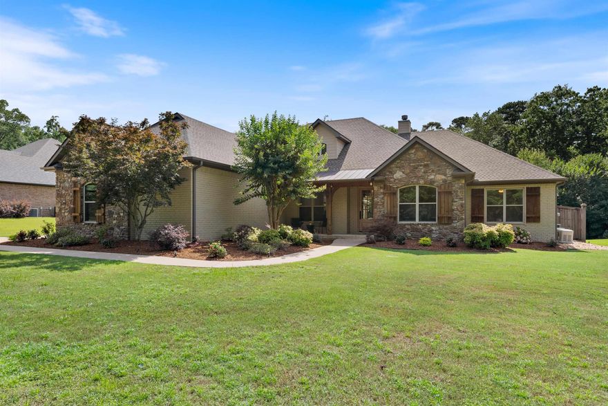 Tucked just outside the Little Rock city limits, this stunning home is a private retreat on nearly an acre close to West Little Rock's dining and shopping. Down a long driveway, the painted brick and Arkansas natural stone exterior creates striking curb appeal, complemented by a welcoming front porch. Inside, the open floor plan lives as a one-story home offering a formal dining room with coffered ceiling, a home office with French doors, and a spacious great room with stone fireplace, custom built-ins, and large windows that frame the backyard oasis. The gourmet kitchen includes a center island, granite counters, new backsplash and dishwasher, gas cooktop, wall oven, microwave, walk-in pantry, and breakfast room. The main-level primary suite features patio access, spa-like bath, and two walk-in closets—one with a FEMA-rated safe room. A guest bedroom with private bath, two additional bedrooms with a shared bathroom, laundry room, and mud room complete the main level. Upstairs offers a 5th bedroom, game room, study nook, full bath, and walk-in attic. Enjoy a saltwater pool, spa, cabana, outdoor kitchen, and more!