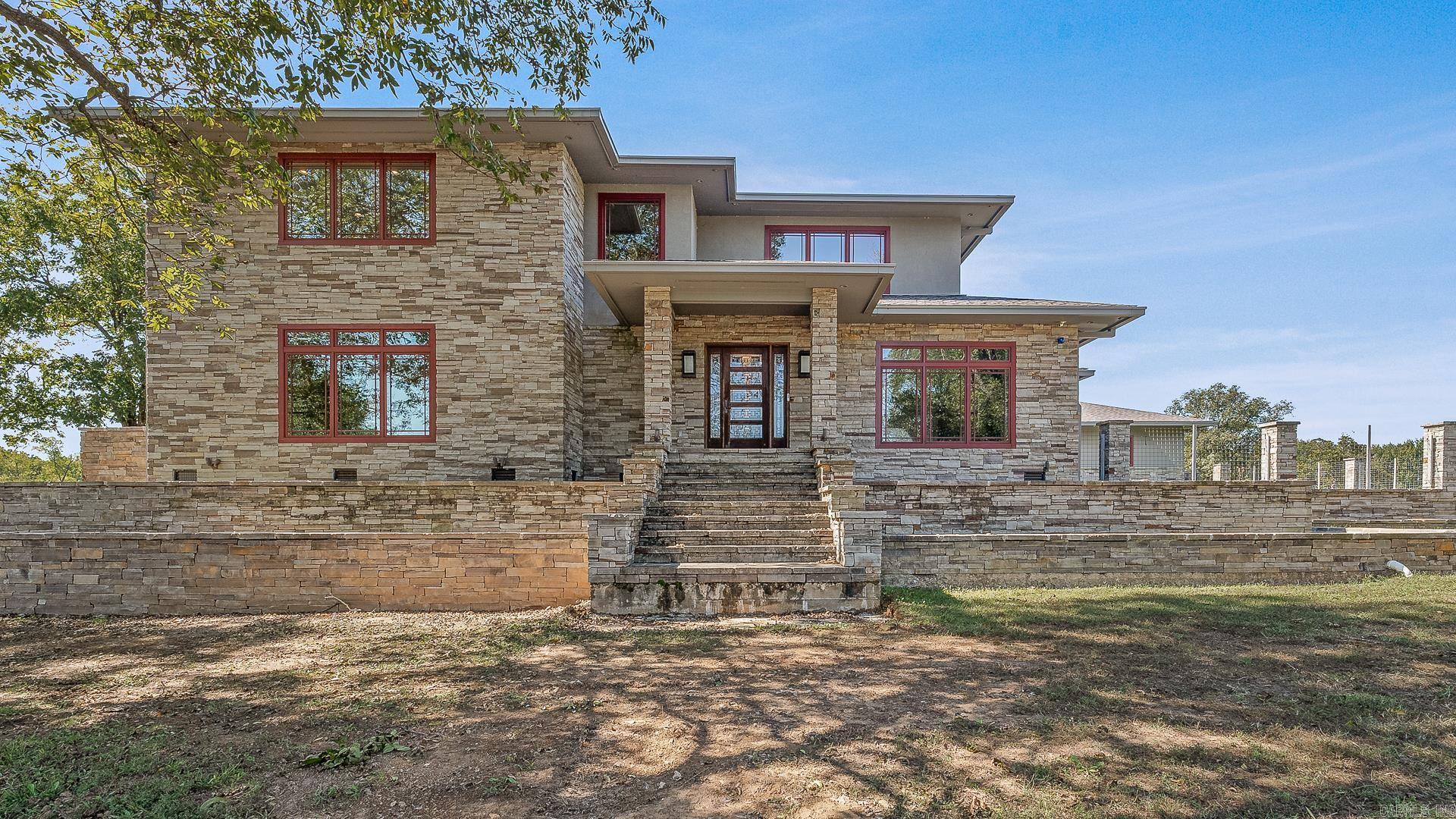 Set on 26 scenic acres, this stunning modern prairieāstyle home is a showcase of craftsmanship, detail, and timeless beauty. Every element was thoughtfully designedāfrom the milled black walnut trim to the heated tile floors and inviting wood-burning fireplace. The gourmet kitchen impresses with quartzite and Corian countertops, an oversized island, double fridge, warming drawer, pantry freezer, and crushed ice maker. The primary suite offers radiant heat floors, a soaker tub, dual sinks, an in-suite washer and dryer, and a spacious custom closet. A floating steel-framed staircase highlighted by a stained-glass chandelier leads to a second living space with fireplace and a full bar featuring a wine cooler, sink, and ice maker. The fully finished heated and cooled garage also includes a snow-melt system. Outside, enjoy a resort-style inground pool with spillover spa, a two-bedroom guest house with full kitchen and dual living areas, a large shop, and a picturesque pond with fountaināan extraordinary blend of luxury, comfort, and craftsmanship.