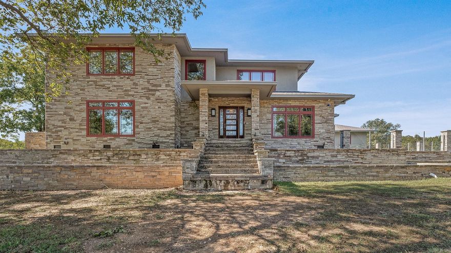Set on 26 scenic acres, this stunning modern prairie–style home is a showcase of craftsmanship, detail, and timeless beauty. Every element was thoughtfully designed—from the milled black walnut trim to the heated tile floors and inviting wood-burning fireplace. The gourmet kitchen impresses with quartzite and Corian countertops, an oversized island, double fridge, warming drawer, pantry freezer, and crushed ice maker. The primary suite offers radiant heat floors, a soaker tub, dual sinks, an in-suite washer and dryer, and a spacious custom closet. A floating steel-framed staircase highlighted by a stained-glass chandelier leads to a second living space with fireplace and a full bar featuring a wine cooler, sink, and ice maker. The fully finished heated and cooled garage also includes a snow-melt system. Outside, enjoy a resort-style inground pool with spillover spa, a two-bedroom guest house with full kitchen and dual living areas, a large shop, and a picturesque pond with fountain—an extraordinary blend of luxury, comfort, and craftsmanship.