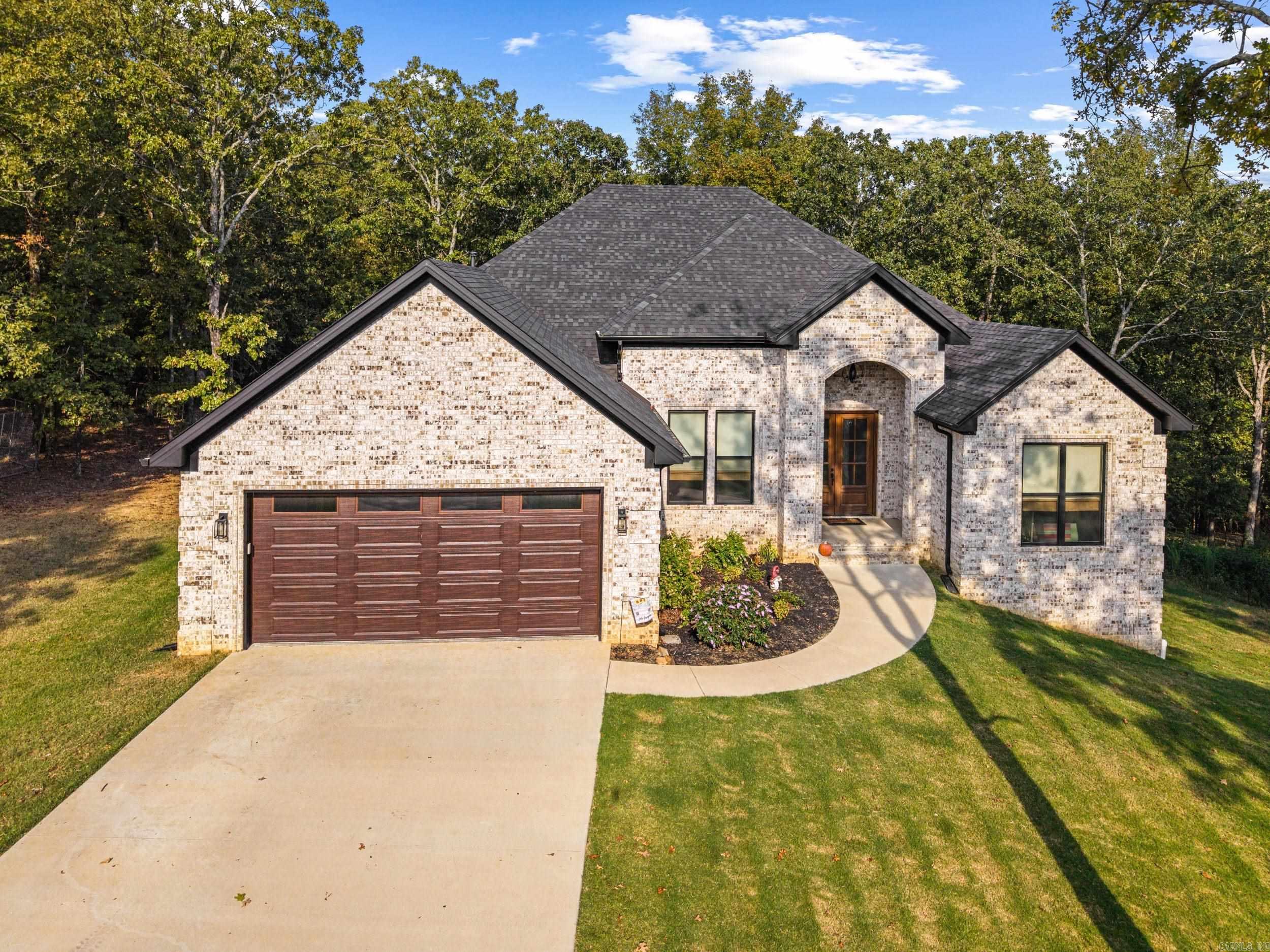Discover this stunning 2023 all-brick home perfectly situated on 4.31 acres with lake access. The property offers the ideal mix of partially cleared and partially wooded land, giving you both open space and natural privacy. Inside, you'll find a spacious open-concept layout featuring a cozy fireplace, a separate dining room, and a large breakfast bar for casual gatherings. The chef's kitchen is complete with double ovens, a walk-in pantry, and plenty of counter space, while the primary suite is a true retreat-boasting a huge walk-in closet and a luxurious bathroom with a soaker tub, oversized tiled shower with dual rain showerheads, and double sinks. Thoughtful details include a laundry room with a sink, built-in dog kennel, and extra storage, plus a tankless water heater, blown insulation in the attic and crawl space, and a propane tank for gas. The walk-out basement/crawl space offers partially concreted areas, perfect for storage or future expansion. Enjoy modern amenities, and energy efficient design all in this one exceptional property!
