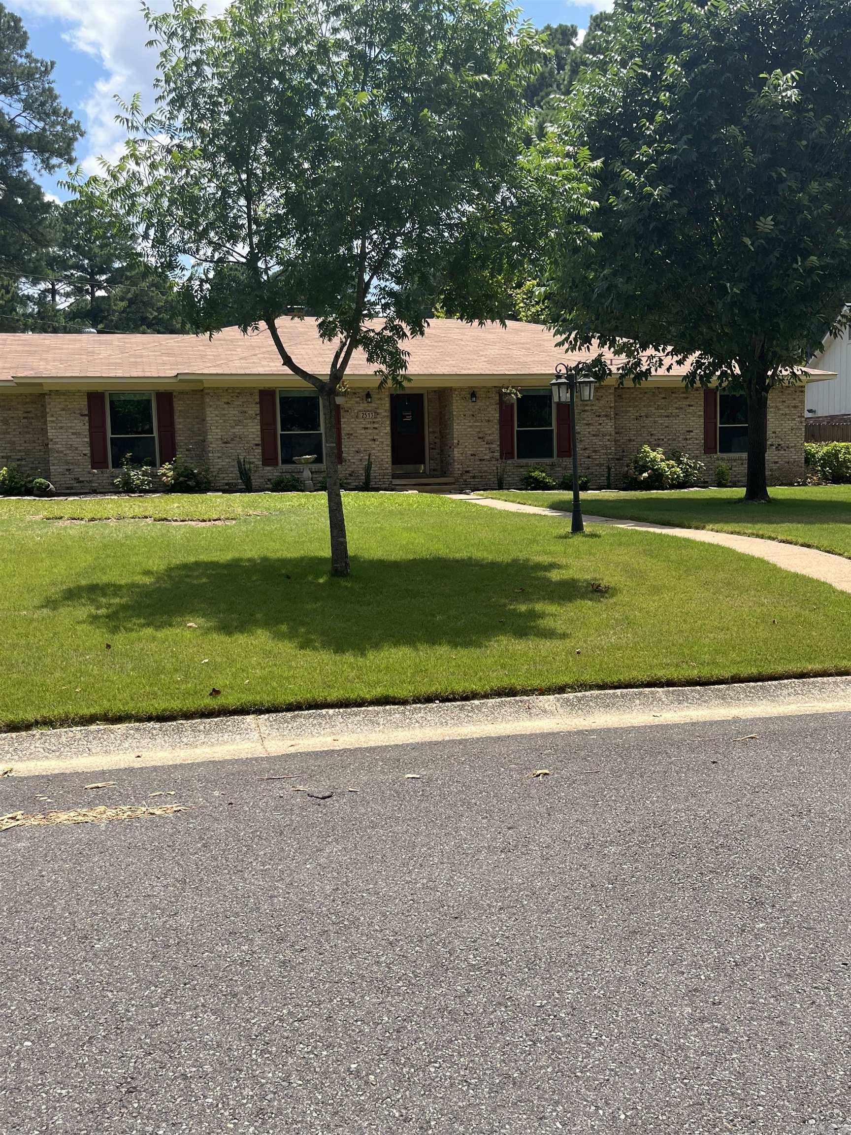 This ranch style home is located just minutes from Southern Arkansas University and boasts four bedrooms, two full and one-half-baths. The sidewalk leads to the front door with wood shutters accenting the home and is beautifully landscaped. To the left of the entryway is the formal living and formal dining room. Updates include kitchen granite countertop. new windows, new flooring throughout, new paint and trim. The kitchen has an abundance of wood cabinets and tile back splash. Appliances include stainless-steel refrigerator, electric cooktop, double oven, built-in microwave and dishwasher. Highlights of the den area are recessed lighting, ceiling fan, gas-starter fireplace and French doors that open on to patio. The hallmarks of the large primary bedroom include a ceiling fan and recessed lighting. The ensuite bath has tile flooring, dual single-sink vanities, and title shower and bath. Two of the three additional bedrooms feature Jack-and-Jill bath with tile floors. Home has laundry room, and carport with storage. This home is on approximately a half-acre and has 2,512 square feet. For your private viewing call Linda Anders with Jan's Realty at 870-904-0147.