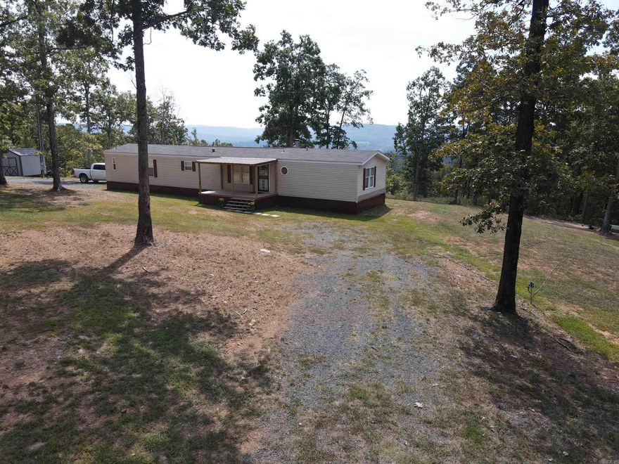 Charming 3-bed, 2-bath mobile home on 20+/- scenic acres in the heart of the Ozarks! This 1,336 sq ft home features a spacious kitchen/ dining, open living room with a cozy wood-burning fireplace, and a functional floor plan. The primary suite includes a private bath with a soaking tub, walk-in shower, and large walk-in closet. Both additional bedrooms also offer walk-in closets. Step out onto the covered back porch and soak in the mountain views and peaceful evenings under dark, star-filled skies. The gently rolling land offers excellent space for gardening, hobby farming, or simply relaxing in nature. Wildlife is abundant—deer, turkey, bear, and small game roam the area. High-speed fiber internet makes remote work, streaming, and staying connected a breeze. County road frontage provides easy access. Located just 10 minutes from Marshall for supplies and local charm, 20–25 minutes from the Buffalo National River, where you can enjoy fishing, kayaking, canoeing, hiking, and numerous outdoor activities. 1.5 hours to Branson, MO. for entertainment, and shopping. A perfect full-time home or weekend getaway! Come make your vision a reality in the heart of the Ozark Mountains!!