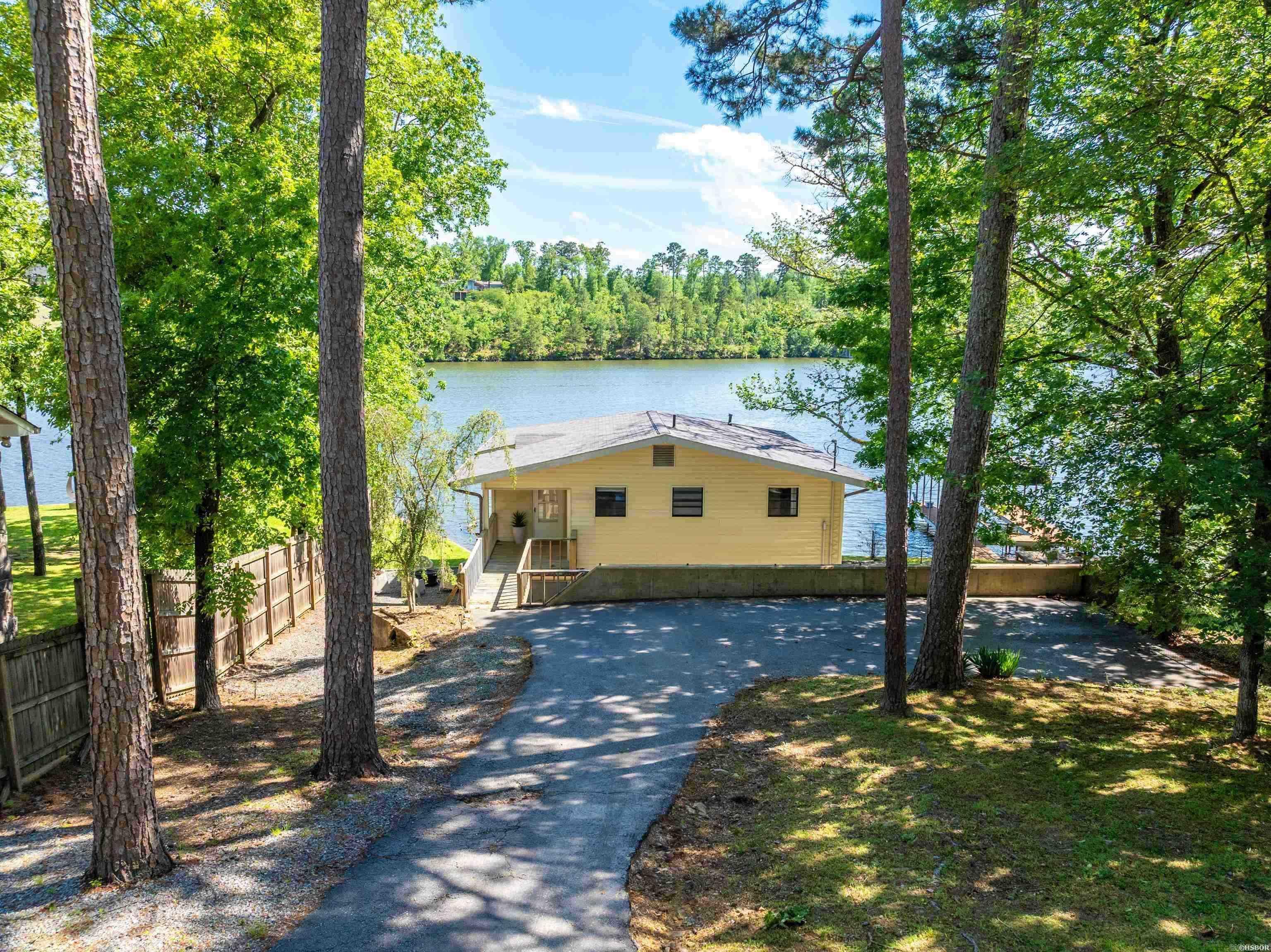 Located on the main channel of Lake Hamilton, this beautifully remodeled 3-bedroom, 1-bathroom lake cottage is the perfect blend of modern design and classic lake charm. Whether you're looking for a serene retreat or a high-performing investment, this property has it all. Recently renovated with contemporary finishes throughout, the home features an open-concept living area filled with natural light, and a fully equipped kitchen with stylish updates. The enclosed sunroom provides a relaxing space for dining, lounging, or entertaining—all with sweeping panoramic lake views. Outside, the grounds are fully fenced with a gated entrance. The spacious lakefront area is ideal for fishing, sunbathing, or simply soaking in the beauty of the water. Sold fully furnished, this turn-key property is ready to enjoy from day one. Currently operating as an active short term rental, this home offers a fantastic opportunity for both personal enjoyment and rental income.