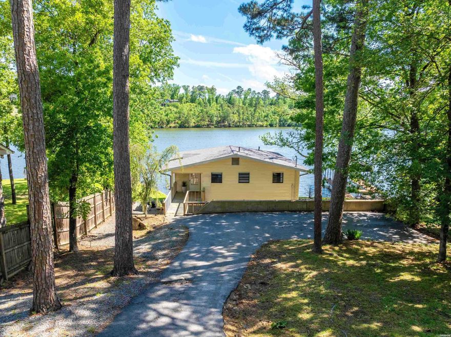 Located on the main channel of Lake Hamilton, this beautifully remodeled 3-bedroom, 1-bathroom lake cottage is the perfect blend of modern design and classic lake charm. Whether you're looking for a serene retreat or a high-performing investment, this property has it all. Recently renovated with contemporary finishes throughout, the home features an open-concept living area filled with natural light, and a fully equipped kitchen with stylish updates. The enclosed sunroom provides a relaxing space for dining, lounging, or entertaining—all with sweeping panoramic lake views. Outside, the grounds are fully fenced with a gated entrance. The spacious lakefront area is ideal for fishing, sunbathing, or simply soaking in the beauty of the water. Sold fully furnished, this turn-key property is ready to enjoy from day one. Currently operating as an active short term rental, this home offers a fantastic opportunity for both personal enjoyment and rental income.