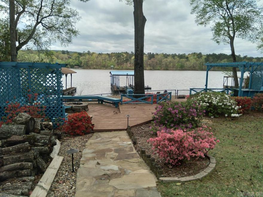 NEW ROOF and NEW SOLAR PANELS fully paid for!  Located right on Lake Hamilton and fed by the Mazarn, this beautiful 2,700-square-foot home has many updated features including a large quartzite island, professional vent hood, and Wi-Fi-enabled appliances and lawn sprinkler system. Solar panel system and whole home generator powered by propane tank allows for energy independence. Downstairs master suite is currently used as a VRBO. It has a kitchen, full bathroom and separate locked entrance from the main floor of the house. It has spray insulation and a storage space that can be converted back to a master closet if desired. The house has two separate whole-home hospital-grade air filters for each air conditioning unit and dehumidifier. Covered floating boat dock and two jet ski ramps. Driving by will not do it justice. The house can only be seen and appreciated from the lake side. Enjoy the lake view while you sip your morning coffee or evening wine on the large, private patio!