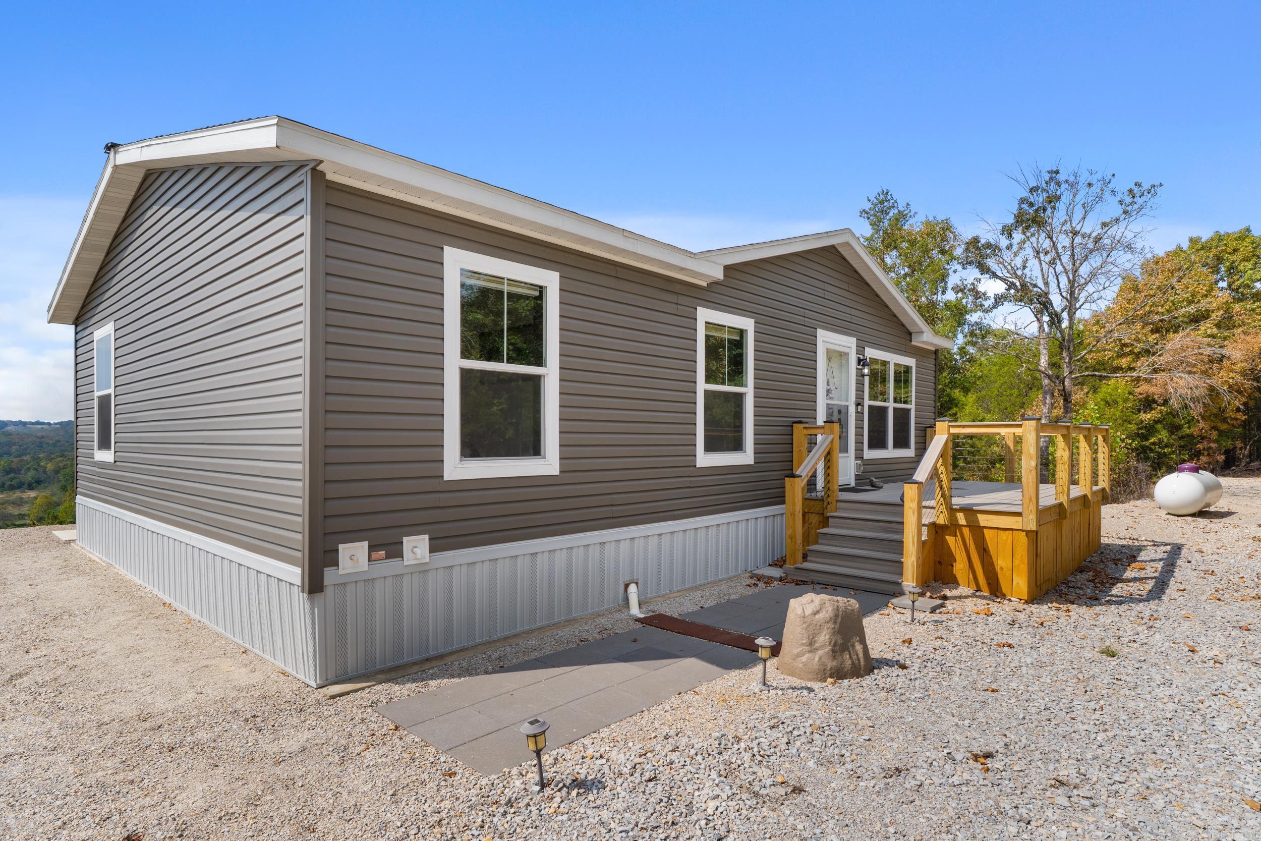 Wow—this is truly a one-of-a-kind lake property! Sitting on approximately 8 acres m/l with breathtaking panoramic views, this 2022 three-bedroom, two-bath manufactured home is move-in ready. The property boasts Corps of Engineers frontage on two sides, giving you a rare and highly desirable location overlooking scenic Pigeon Creek on Norfork Lake. Just minutes from lake access and fronting a paved state highway, convenience meets natural beauty here. A 30x50 pole barn/shop and large gravel parking area provide plenty of space for boats, RVs, or equipment, making this a dream setup for lake lovers, hobbyists, or anyone seeking extra storage. With unmatched views, prime frontage, and modern living, this property offers everything you could want in a lake retreat—don’t miss your chance to own it!