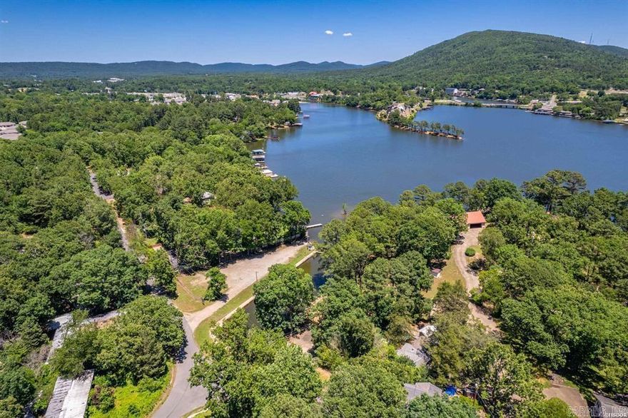 This 3 bedroom adorable home has a great view of Lake Hamilton! It also includes a lake lot across the street with a boardwalk and a boat ramp at the private park. Enjoy the enclosed porch with beautiful views, storage shed/workshop, and completely fenced yard. 3 bedrooms, 1.5 baths, eat-in kitchen and cozy living room. New roof in 2023, new gas heater in 2025. This would be a great starter home, weekend getaway to enjoy Lake Hamilton, or a rental. It has been lovingly maintained and ready for a new owner.