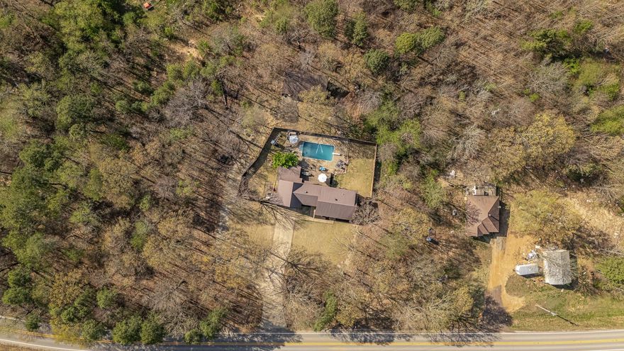 Welcome to the market, 8457 Highway 163 in Harrisburg, Arkansas! If you've been waiting for your dream home with amenities galore, nestled in mature shade trees for privacy on your own acreage, step right in! This gorgeous country estate boasts 3 large bedrooms and 2 full bathrooms, with the primary situated on the main level. Not only can you enjoy both formal living and dining areas, but a large den welcomes you off the dining room, perfect for entertaining guests or enjoying quiet nights at home with family. Custom granite countertops and cabinetry adorn the kitchen and bathrooms, and modern luxury vinyl plank flooring will walk you through the majority of the home. Fire up the kitchen for a home cooked feast! Your guests may share a toast at the kitchen bar and dine in your formal dining area. Are you an avid outdoorsman? Or just enjoy the tranquility of reading your favorite book lounging by the gorgeous in-ground pool! Do you enjoy tinkering or wood working? This estate has a shop waiting for you beyond the wood privacy fence line, as well as a firepit area ready for s'mores and campfire chats! If you're not the campfire type, your power is secured with a full-home generator.