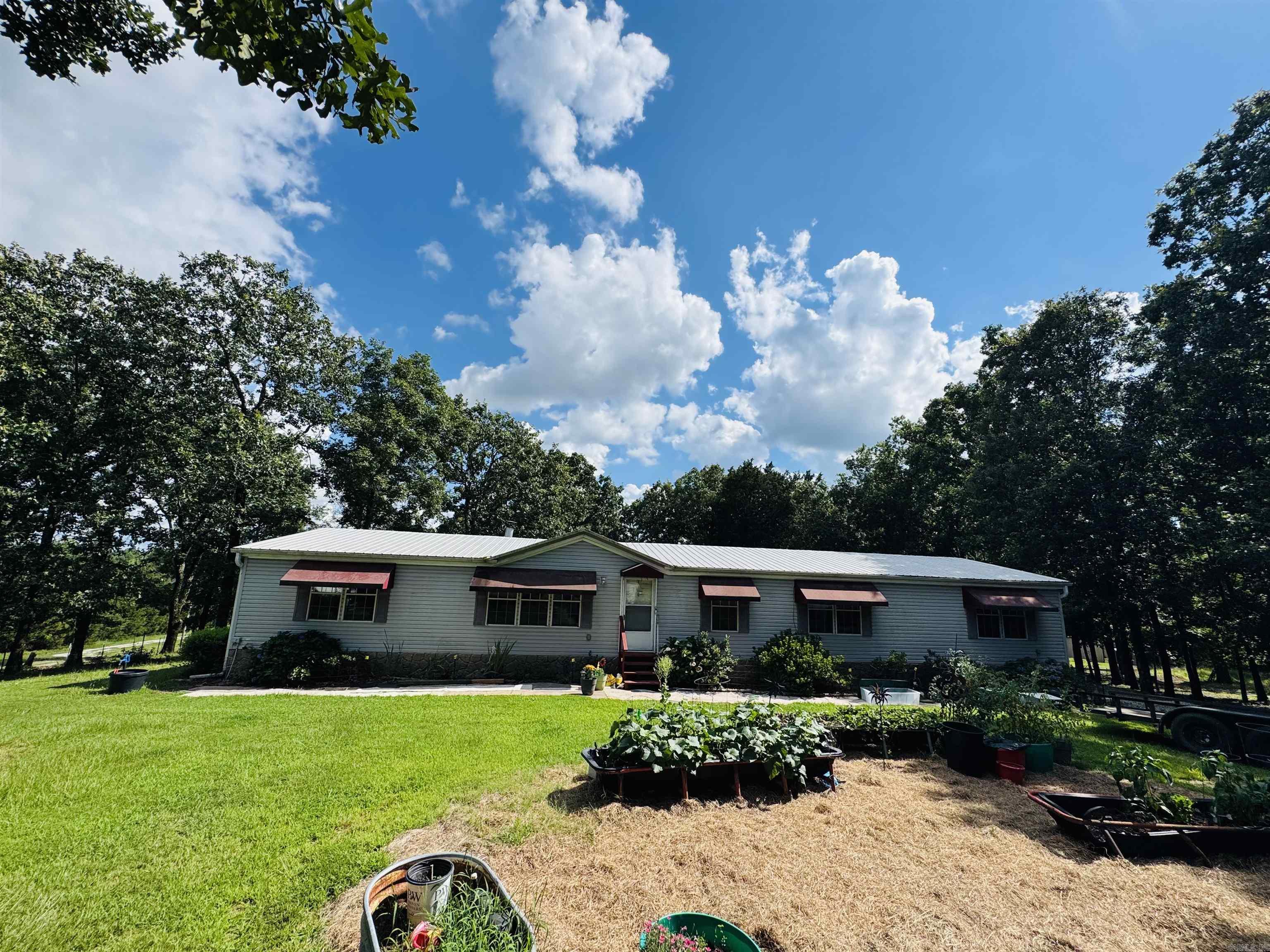 If you're looking for the farm life, THIS IS IT! Check out this beautiful 38+ acre compound ready for you to call home... This one owner 2240 sq ft double wide is sitting on a permanent foundation with an insulated metal roof with warranty. As you walk in the front door, there is a huge living space with a wood burning fireplace and open concept to the kitchen. Home is pretty much original from when purchased new and has been well taken care of. The pastures have had cattle/horses in the past ran on it, and is now used mostly for hay ground. The back side of the property is wooded with tons of wild life and goes to top of hill with a picture perfect view. Property has LOTS of storage including a barn with stables/tack room, 2 bay red iron shop, 2 carports and a covered barn in pasture as well. Lots of love has been given to this land and the flowers and gardens make it feel very welcoming. Lastly there is an in-ground storm shelter and a well drilled to top it off. This homestead is ready for the next family to love. Call your realtor and schedule your showing today to make this Home!