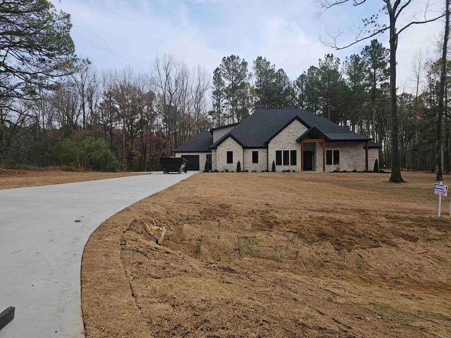 This 3433 SqFt sanctuary, with 5 bedrooms and 4.5 bathrooms, enveloped in coziness features casement windows that gently invite natural light, while a regal 12ft ceiling graces the kitchen and living room. The warm embrace of 10ft ceilings downstairs sets the perfect ambiance, accompanied by gas logs in the living room and a rustic wood burner on the porch. The master suite features a walk-in shower, while an inviting in-law suite and two bedrooms accompany the lower level. Upstairs features a captivating bonus space. This home also offers wood flooring throughout, an acre wooded lot, and a 3-car garage.