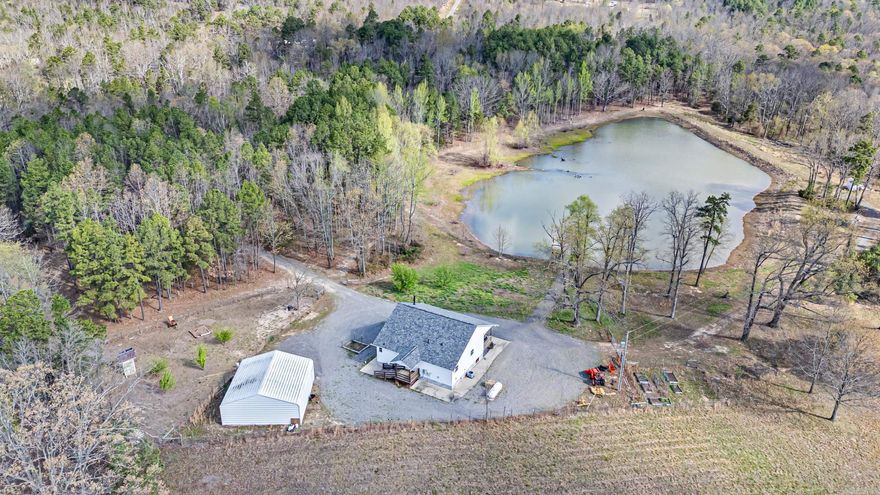 This incredible property is a must see! Built in 2017 and set on 23.46 acres, it delivers the perfect blend of comfort, functionality, and opportunity. A breathtaking 3 acre pond loaded with catfish, largemouth bass, bluegill, and crappie serves as its centerpiece, with full perimeter access, a gravel drive across the dam, wooded trails, and a large dock. Inside, the kitchen, bathrooms, and laundry room feature granite countertops, shaker cabinetry, and a stylish backsplash that ties it all together. Step outside to an expansive deck overlooking peaceful surroundings, with the entire acreage fully fenced for added privacy and usability. A two bay shop with overhead wiring, retractable extension cords, and workbenches offers versatility for work or hobbies. Additional features include an on demand water heater and an owned propane tank. With established fruit trees, garden space, wildlife, and room to spread out, this property is ideal for recreation, homesteading, or creating your own retreat. Truly a rare find!