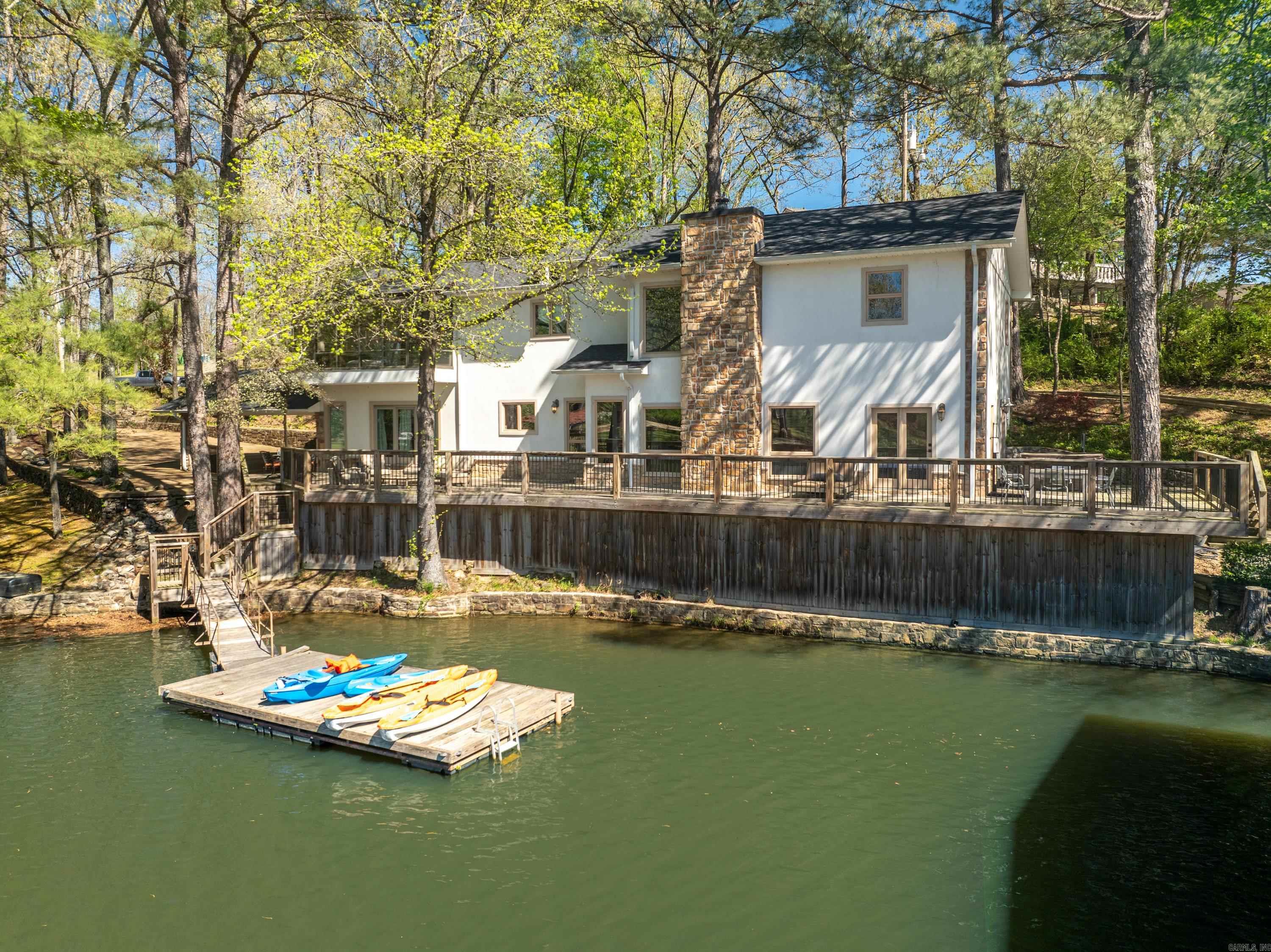 Wonderful home located on a quiet cove on Lake Hamilton on just under 1 acre. Sleeps 18 comfortably and has been a very successful short term rental. The home is being sold fully furnished with mostly Pottery Barn furniture. The main level has an open living, kitchen, dining and TV area. One bedroom and a bunk room away from the main living area is perfect for kids is also found on the main floor. The second floor has four bedrooms. The primary bedroom is very large with a spa like bath and a sunroom with a tub. The exterior is a retreat with a deck around two sides that overlooks the cove. There is also a hot tub, outdoor shower, fire pit, covered dock with electrical and a swimming dock. The property also has area that is large enough for an RV with electrical hook ups and would be large to allow for an additional home to be built. The property is located outside the Hot Springs city limits and does not require a license for short term rental use.