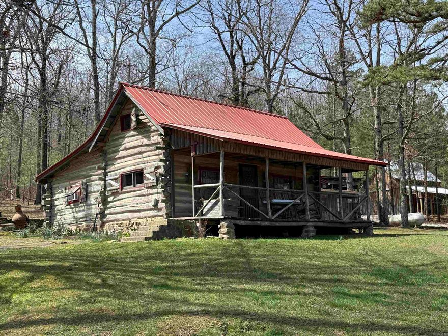 20 +/- wooded acres in Leslie, AR with Hurricane Creek flowing through the property. Features a 667 sq ft log cabin with rock fireplace designed for heat efficiency, 1-bedroom, spacious living area, kitchen, and full bath with rock shower. Covered walkway connects to laundry, wood room, and carport. Property includes public water, electricity, high-speed fiber internet, plus a well with hand pump. Improvements include a 16x24 barn with loft and side storage, greenhouse, fenced garden, chicken coop with covered run, and fenced area for small livestock. Additional living spaces include the “Studio Cottage” with full bath and efficiency kitchen, the creekside “Lean-to Cabin” with screened sleeping area, and a “Dry Cabin” with bed, wood stove, and writing desk. Ideal for homestead, recreation, or investment.