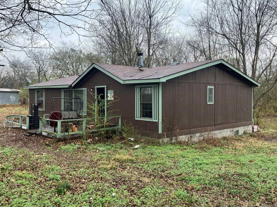 Super location in the heart of Mena, very convenient to shopping, dining etc. 1990 Manufactured home on a permanent foundation with a newer roof. newer paint and a nearly new heat pump.   Great wood burning stove inside.  Floorplan is split with the primary on one side and two bedrooms on the opposite side. The inside is in the process of being cleaned up / packed up.  Areas of the sub-floor are needing to be redone (from some past water damage) and both bathrooms are needing some updating (one needs to have a tub/shower put back in) along with other general cosmetic interior updates, but once done this one will be a really nice home or even a rental.  Home sits on a double lot with mature trees and lots of lovely spring flowers and a carport.  Sale subject to bankruptcy court approval.