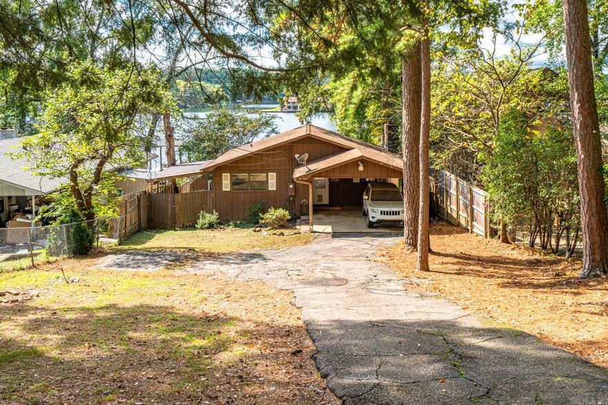 This cozy waterfront cottage sits on a 50' wide lot with level access straight to the water. Every inch of the shoreline is maximized; you are sure to enjoy the covered boat dock and boat launching ramp perfect for personal watercraft, kayaks, and paddle boards. Just a few steps from the backdoor, and you're out on the water! There is also covered storage perfect for your water toys and outdoor gear. Inside, big water views greet you from nearly every room. The living room is especially inviting with its vaulted ceiling and brick fireplace; kick back and relax after a day on the lake. The cottage's open layout blends indoor and outdoor fun. Whether you are enjoying the patio with a BBQ or lounging by the fire, every moment at this lake cottage is an ideal mix of ease, comfort, views, and fun. Interested in investing on Lake Hamilton? This property is located outside the city limits with no short-term rental permit required. [Buyers, this property is being sold AS IS. Inspections (if desired) must be completed prior to offer submission. All offers must include proof of funds or a lender pre-approval letter and a minimum of 30 days for offer expiration. Agents see agent remarks.]