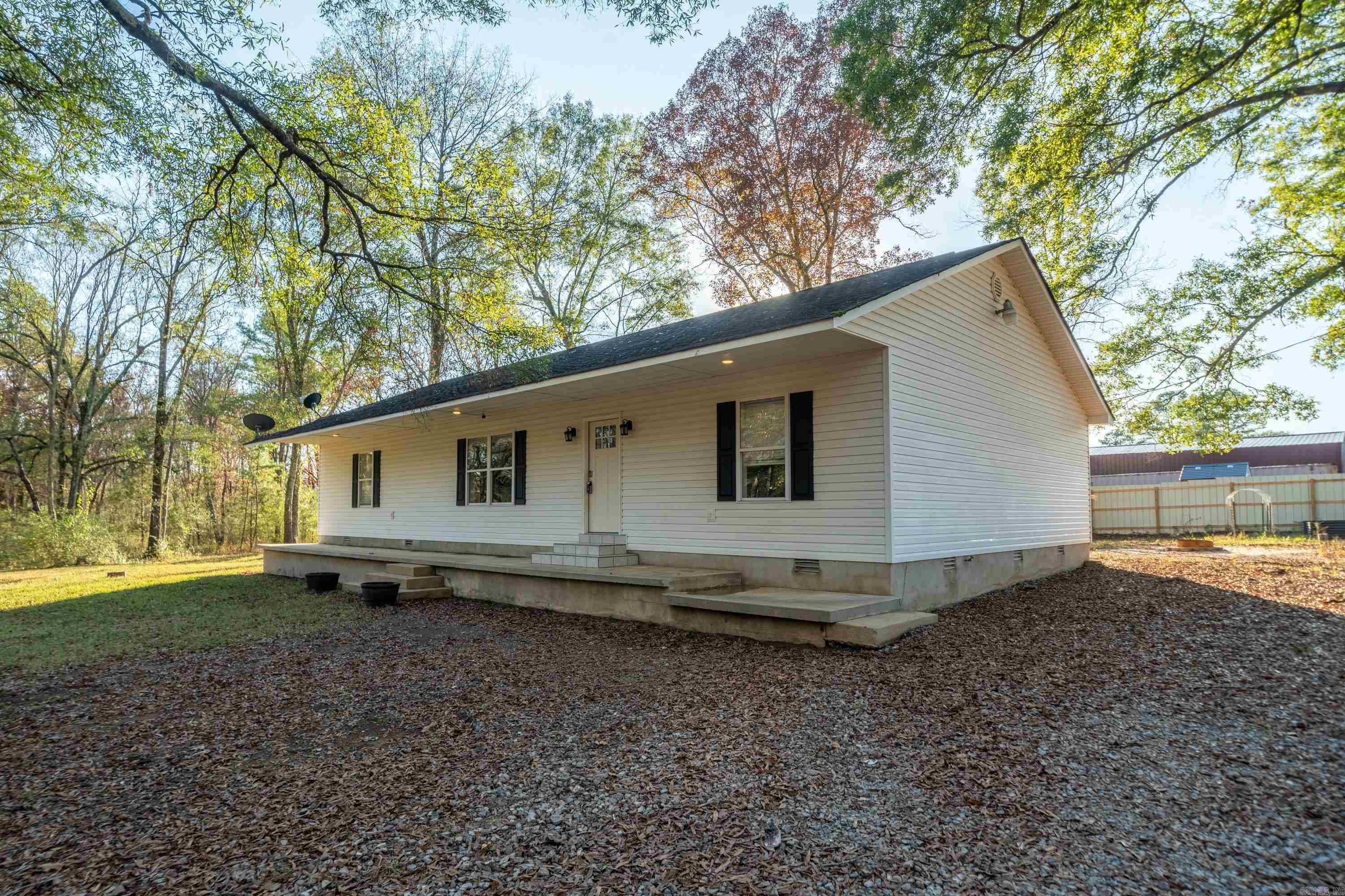 This inviting 3-bedroom, 2-bathroom home, built in 2001, is set on a nearly 5-acre private lot surrounded by beautiful trees, offering both tranquility and plenty of space for outdoor activities. With 1,800 sq. ft. of living space, the home features a spacious living room with hardwood floors, creating a warm and welcoming atmosphere. The updated kitchen is perfect for everyday cooking, with white cabinets, granite countertops, and stainless steel appliances, plus a convenient dining area for family meals.  The master suite is a true retreat, featuring a spa-like bathroom with a double vanity, walk-in shower, and a relaxing jacuzzi tub. Two large walk-in closets provide ample storage. The two additional bedrooms are cozy with carpet, while the wet areas are finished with easy-care tile.  Outside, you’ll find plenty of room for gardening, chickens, or creating your dream outdoor space. With its peaceful wooded surroundings, this property offers the perfect balance of privacy and natural beauty. The refrigerator, washer, and dryer are included, making this home move-in ready. Don't miss out on this wonderful property—schedule a showing today!