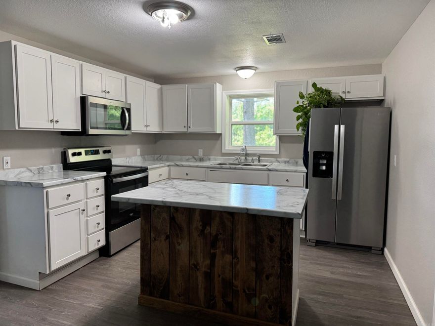 Enjoy privacy in this charming 4-bedroom, 2-bath home located at the end of a quiet street, backing to expansive wooded land. This well-maintained property features a new metal roof, durable LVT flooring throughout, and tilt-in vinyl windows. The spacious primary suite includes an en-suite bath for added comfort. The inviting living room offers a cozy wood-burning stove, perfect for cooler nights. The kitchen comes equipped with stainless steel appliances and a new washer and dryer. Step outside to a fenced backyard—ideal for pets or play—and a 24x30 detached shop with an additional fenced area behind. City water, 1,608 sq. ft. of living space, and priced at $259,900, this home offers space, function, and a peaceful setting.