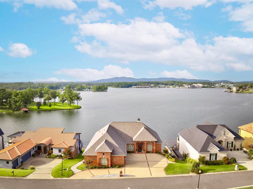 A rare offering on Lake Hamilton, this exceptional custom-built waterfront estate blends architectural refinement with understated luxury. Designed for elegant living and effortless entertaining, the home features 5 bedrooms, 5.5 baths, a gourmet kitchen with granite countertops professional grade appliances, and a separate lower-level suite with full kitchen — ideal for guests or multi-generational living. The gracious primary suite offers a spa-like retreat with an expansive walk-in closet, while a dedicated office adds practicality to the timeless design. Outdoors, enjoy a thoughtfully created cart path to the water, refinished dock and boat lift, and inviting entertaining spaces overlooking the water.   A true expression of Southern elegance, every detail adds a touch of Lagniappe on the lake— that “little bit extra” that sets this property apart. (Full house generator is present and a full list of updates and improvements available upon request.)