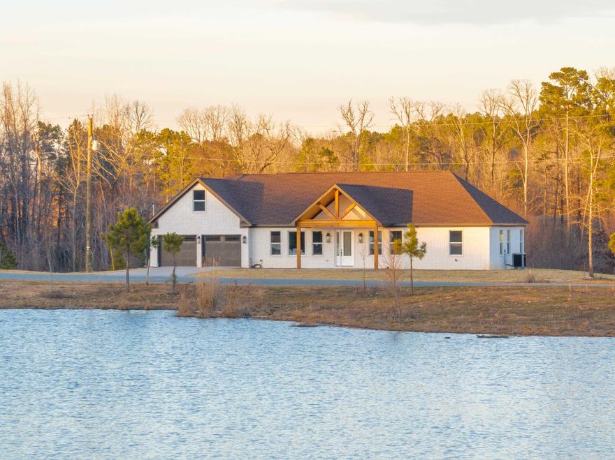 Welcome to this stunning waterfront, newly constructed home nestled on 3 acres in a gated community. Boasting 3 bedrooms and 3 luxurious bathrooms and bonus room, this all-brick masterpiece is complemented by warm wood accents. Living area features a vaulted ceiling with wood detailing, creating a grand yet inviting atmosphere. A gas log fireplace adds a cozy touch to the living room, and the master suite includes its own private fireplace, perfect for relaxation. The heart of this home is the gourmet kitchen, complete with gleaming granite countertops, stainless steel appliances, 2 dishwashers and soft-close cabinets. The luxury vinyl flooring throughout ensures durability while maintaining a sleek, modern aesthetic. The master suite is a true retreat, featuring a large soaking tub, a separate walk-in shower with a rain head, and a double vanity for ultimate comfort and convenience. Enjoy the serenity with unobstructed views of the community lake, a two-car garage offers plenty of storage space, and a safe room for added peace of mind. This home is designed for both luxury and functionality, making it the perfect place to call your own. Don’t miss out on this rare opportunity!