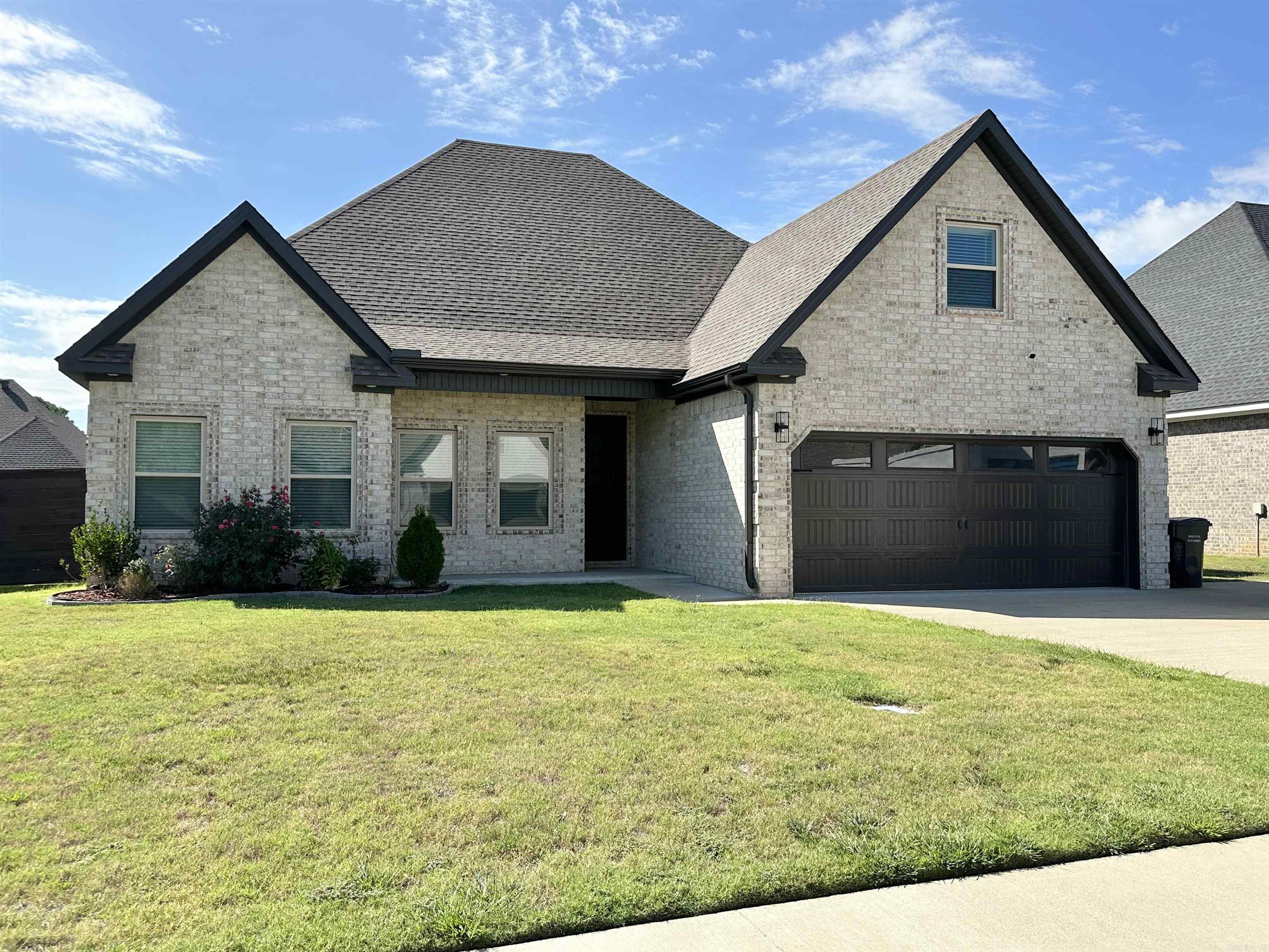 This elegant brick home, constructed in 2022, is situated within the Eden Hills Subdivision of the Brookland School district and falls within the city limits of Jonesboro, benefiting from CWL services. Home has 5 bedrooms & 3 full baths, with 12-foot raised ceilings spanning the great room, kitchen & dining area. Multiple windows surround the dining area, providing abundant natural light. The master suite offers tray ceilings, an en-suite bathroom with double sinks, a soaker tub featuring tile surround, a custom-tiled shower with a glass door & an oversized walk-in closet. Luxury vinyl flooring extends throughout the great room, bedrooms & hallways, while the laundry room, kitchen & bathrooms feature tile flooring, and carpeting is limited to the stairs. Amenities include crown molding, ceiling fans, wood shelving units in all closets, granite countertops in both the kitchen and bathrooms, a tiled backsplash, a tankless water heater, gas log fireplace, screened porch, patio & foam insulation + upgrades: front porch, gas stove/griddle/double oven, pot filler, 3rd bath, 3rd parking, garage & front door, microwave drawer, vent hood, smart mirrors. Horizontal slat fence added 2023
