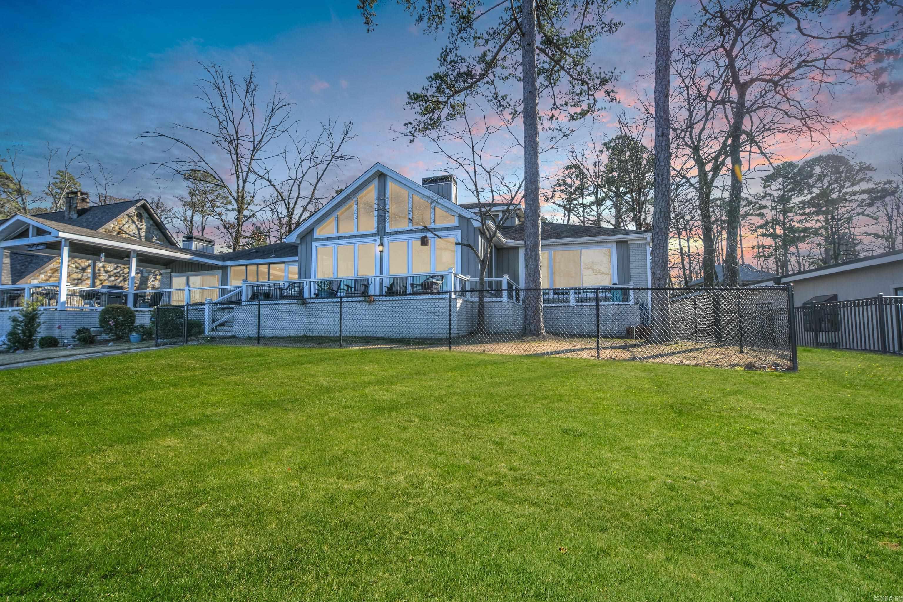 Welcome to this stunning lakefront estate on Lake Hamilton. This. home on a .84-acre lot offers 101 feet of water frontage, a double-slip boat dock with hydraulic lifts, and wrap-around decks perfect for entertaining or relaxing by the water. The main level features a spacious living room with vaulted ceilings, walls of glass, and a fireplace, flowing seamlessly into a formal dining area and a gourmet kitchen with an island bar, double ovens, an under-cabinet ice maker, and walk-in pantry. A family room with a wood-burning fireplace, three bedrooms, three baths, an office, and a laundry room complete the first floor. Upstairs, two bedrooms and a stylish bath provide additional space for guests or family. The exterior blends gray brick and vertical siding with white trim, offering modern curb appeal, while the fenced backyard and lush landscaping enhance outdoor living. Experience luxury and serenity at this one-of-a-kind lakefront property. Schedule your private tour today!