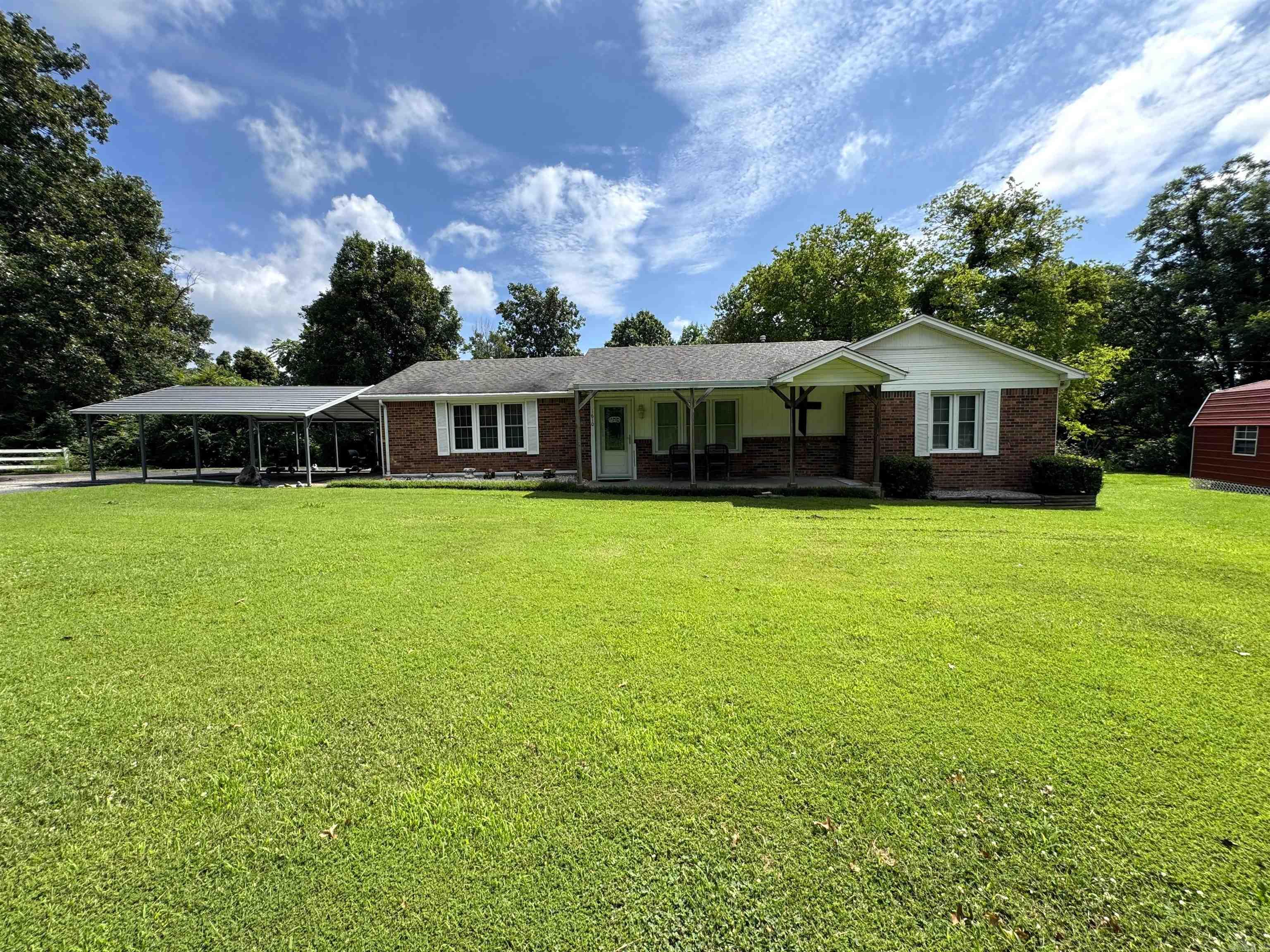 1610 S. 12th Ave. in Piggott, AR is a 3 BR, 1.5 BA, 1,382 SF home situated on a 0.37-acre lot. This single-family residence is a classic ranch-style home. This home features a single car carport, an 18x20 detached carport, and a semi-circle driveway for ample parking. There is a 12x16 outbuilding and an 8x16 lean-to also included with the property. The large, covered deck is perfect for relaxing evenings outdoors. The interior features an open concept design with a separate laundry room. The cozy family room is equipped with an electric log fireplace, providing the ambiance of a real fire without the maintenance, and beautiful luxury vinyl flooring. The 3 bedrooms are ideal for families or guests, and the 1.5 baths offer functionality for daily living or hosting. The multiple built-in cabinets throughout the home provides a generous amount of extra storage. If you are looking for a home nestled on the edge of town, offering a country-like feel, but still located on a paved road-look no further.