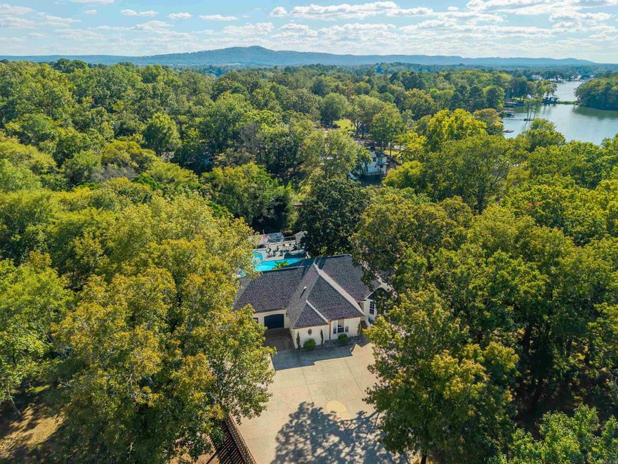 ~More Land. More Privacy. Now $50k less ~ This beautifully updated Lake Hamilton home is truly a private resort. From the elegant front elevation to the tropical pool & cabana, every detail is designed for entertaining. Set on over half an acre plus an adjoining parcel adding approximately 1.73 additional acres, this property offers exceptional space, privacy, & rare lake value. Inside, the open-concept layout features a bright white kitchen w/quartz countertops, gold accents, stainless appliances, & a custom coffee/wine bar w/designer tile backsplash. The primary suite on the main level includes a spa-style bath w/soaking tub, dual vanities, & walk-in closet, along with a main-level office. Downstairs offers three bedrooms, one bath, laundry, & flexible family/game room. Outdoors, enjoy an in-ground pool, expansive composite decking, & furnished cabana w/lush tropical landscaping. Includes a private boat launch & covered boat slip on Lake Hamilton, now offered with a $50,000 price reduction & added acreage. Centrally located near Hot Springs attractions & selling furnished & turnkey. (additional parcel shown in photos) ?? Virtual Tour:  https://www.youtube.com/watch?v=vtugVU2VIIE