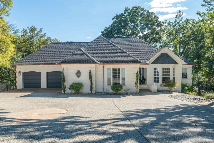 This beautifully updated lake Hamilton home is truly a private resort. From the elegant front elevation, to the tropical pool and cabana, every detail has been designed for entertaining. Set on over half an acre, it offers space, privacy, and luxury combined. Inside, the open layout features a bright white kitchen with quartz countertops and gold accents, stainless appliances, and a custom coffee and wine bar. The primary suite on the main level showcases a bold accent wall, spa-style bath, dual vanities, and a large walk-in closet. In addition, a dedicated office on the main floor provides the perfect workspace or hobby area. Downstairs, you'll find 3 bedrooms, a bath, laundry room, and flexible game/family room. Outdoors, the backyard is a showstopper—featuring an inground pool with diving board, expansive decking, and a furnished cabana with hanging chairs and lush tropical landscaping. At night, the soft lighting creates a magical poolside ambiance. Best of all, the property includes its own private boat launch and covered slip on Lake Hamilton.Centrally located in the heart of Hot Springs, selling tastefully furnished and turnkey, this home delivers the ultimate lake lifestyle