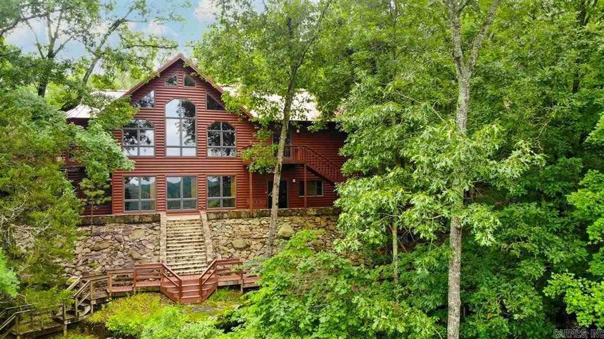 Inspired by the great mountain lodges of the West, this extraordinary riverfront retreat at 100 Trout Way in Judsonia sits high on bluffs overlooking the legendary Little Red River, known for world-class trout fishing. Massive timber beams & rich wood finishes create a warm, lodge-style feel throughout the home.  Designed for entertaining & relaxation, enjoy stunning sunset views over the river, evenings by the pool, or peaceful walks along wooden boardwalks that wind past waterfalls to the river’s edge. Inside, natural materials shine—most floors are wood, while unique limestone flooring features visible fossils.  The property also includes a 650± sq ft guest house with full kitchen (not included in main square footage), ideal for visitors or extended stays. A full-home generator provides added peace of mind. Over 20 acres are available to roam.  Amenities & Features: blufftop river views, pool, scenic boardwalks to the river, heated & cooled 3-car garage, epoxy garage flooring, boat slip access, lodge-style beams & finishes, limestone fossil flooring, & extra exterior storage.  Most appliances/furnishings negotiable with acceptable offer (some exclusions may apply).