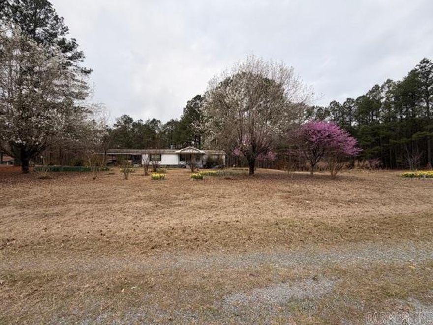Charming country property on 7.41 acres in Louann, AR! This 1,560 sq ft manufactured home, built in 1999, offers 3 bedrooms and 2 bathrooms with plenty of potential to make it your own. While the interior could use some updates, the setting is truly special—featuring 3.68 wooded acres that could serve as an additional homesite or private retreat. The land is dotted with blooming daffodils and other beautiful flowers, creating a peaceful, scenic atmosphere. A shop and storage shed provide added functionality for hobbies or extra storage. Great opportunity for those seeking space, privacy, and potential in a rural setting.