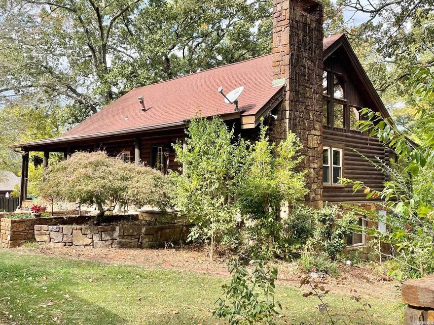 Discover your secluded sanctuary in the heart of Hot Springs, just 1/2 mile from Oaklawn Casino. This exquisite 2600+ sq ft authentic log home is a blend of rustic charm and modern comforts. The vaulted ceilings adorned with exposed log beams welcome you, creating an inviting and spacious ambiance filled with an abundance of natural light. The heart of this home is the great room, anchored by a native stone fireplace, showcasing the knotty pine floors that run throughout. The kitchen boasts granite countertops, an under-mount sink, and stainless steel appliances. One of the remarkable features of this property is the captivating outdoor space, which feels like a hidden oasis. Explore lush gardens, take leisurely strolls on meandering paths, or simply relax in your own outdoor haven. It's a place where you can create lasting memories and enjoy the natural surroundings. In addition to the main living space, the lower level is thoughtfully designed to be handicapped accessible, making it the perfect candidate for an in-law suite or accommodating guests with ease. This home is licensed as a short term rental with City of Hot Springs.