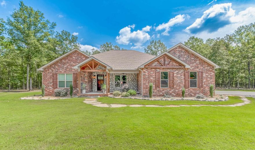 This beautiful 4 bedroom/3 bath home is ready for you to call home. Situated on a lovely wooded 5 acre lot, this stunning property is move-in ready.  As you step inside, you'll be greeted by extra wide doors throughout.  The home features a front great room with exposed beams and a gas log fireplace.  The kitchen area has a beautiful chandalier for over a dining room table.  The spacious kitchen with an extra large island makes for a breakfast bar and is perfect for gatherings. The kitchen offers tons of cabinets, granite countertops, free standing range w/doublee, refrigerator, and vent a hood.  The expansive owner's suite with a large bath that includes a large shower, separate soaking tub, large closets, and double vanities. There are three additional spare bedrooms, one with a private bath, and a Jack & Jill bath.  Wonderful home for any family and 5 wooded acres are exceptional!