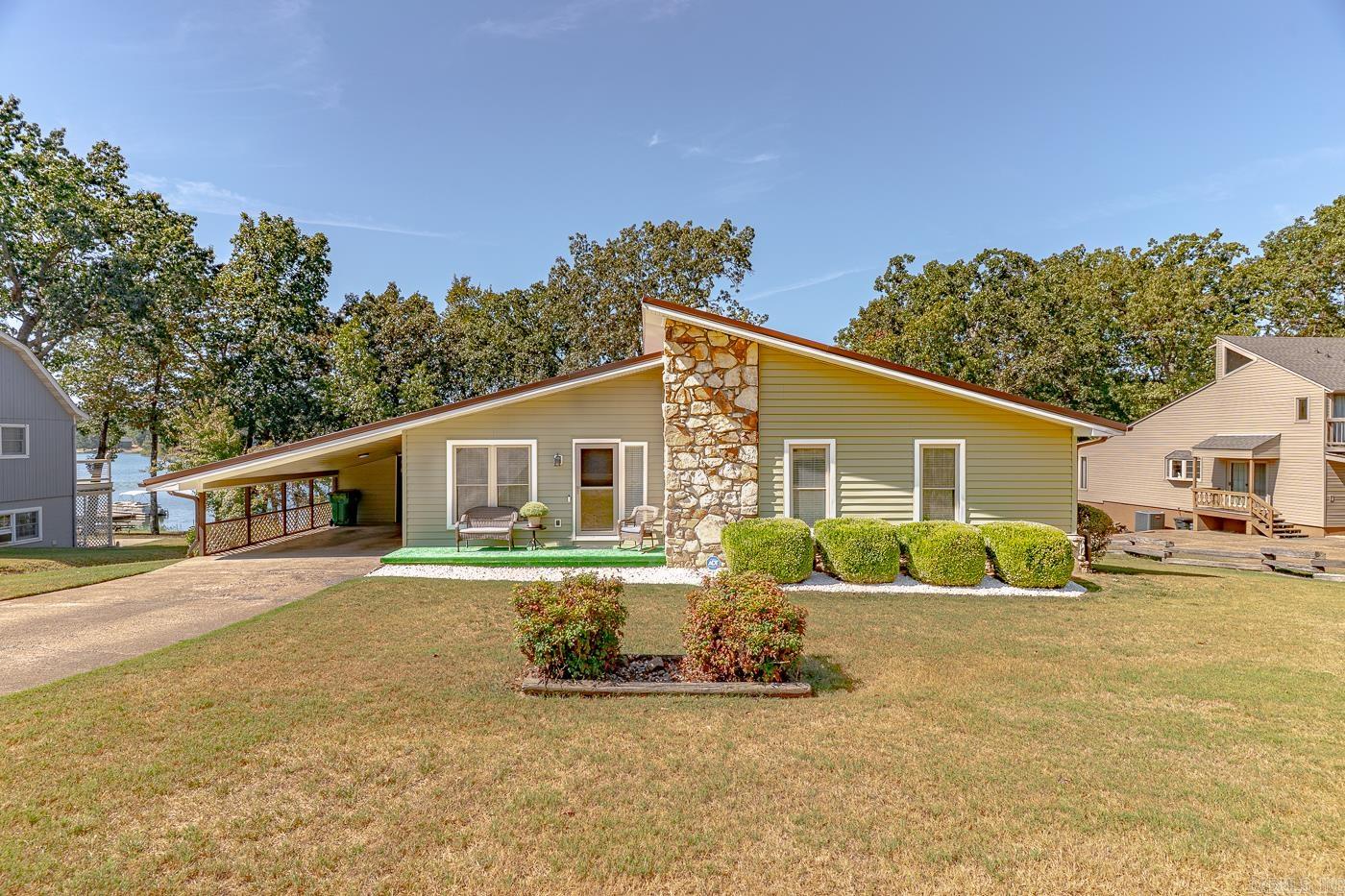 Welcome to Market 1213 Peridot Lane of the Crown Add. in Horseshoe Bend, Arkansas on Majestic Crown Lake. Situated on a .50 +/- acre lakefront lot that features artistic landscaping & design, is a Mid-Century Modern Ranch style home wrapped in stone & 2022 vinyl, topped with a 2021 metal roof, and accented by a cozy front porch, wood deck, attached carport with storage room, and million dollar lake views. The interior features 1,773 sf of well laid out living space that includes a living room with fireplace with stone surround, galley kitchen w/ stainless steel appliances & bar seating, dining room, insulated 3 season porch, Master bedroom with en-suite featuring a walk-in tub, 2 guest bedrooms and guest bathroom with shower/tub combo. Check out the 210 sf basement w/ storage area and encapsulated crawl space with dehumidifier, and sump pump. You'll love 640-acre Crown Lake and all the amenities that Horseshoe Bend has to offer while being located within a 3-hour drive to Little Rock, Memphis, and Branson. This prime piece of real estate is a jewel in the Crown. If you're ready to start living the lake life, call today to make this lakefront house your home or home away from home.