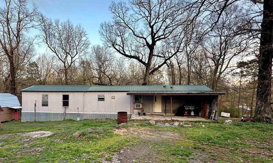 Great fixer-upper with lots of potential! NO RESTRICTIONS. 2 bed, 2 bath mobile home on 1.3 acre m/l. Extra lot with its own septic, water, and electric. Big covered front porch. Spacious living room and kitchen. Large main bedroom with a garden tub and separate shower in the bathroom. Beautiful oak trees scattered throughout the property. Large backyard. Has a 12x16 storage shed with a loft and electricity. With a little fixing up, this would be a stunning home or rental property! Just a minute to Cove’s local amenities and just 16 miles up Mena. Get it before it’s gone. SEE AGENT REMARKS