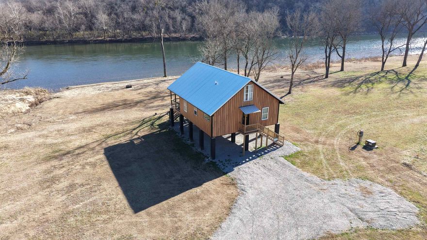Welcome to Eagle Hollow Retreat, a custom-built riverfront cabin tucked away in a secluded setting near Mountain View and Melbourne, AR. This brand-new, fully furnished home features over 100 ft of White River frontage in a prime fishing spot known for rainbow trout and smallmouth bass, with eagles often soaring overhead. The cabin includes 3 bedrooms and 2 bathrooms, with custom wood finishes throughout. There is a king bed in the primary suite and queen beds in the others. Each room is complete with a personalized vanity table. The kitchen is fully stocked and outfitted with custom butcher block countertops, crystal breakfast glasses, silver-plated flatware, and Pfaltzgraff dinnerware.  Enjoy river views from the covered 12x30 deck or relax by the firepit and seating area. The property also offers boat ramp access, a seasonal sandbar, a fishing dock, and a fully graveled area under the home for extra parking or outdoor space. Whether you're looking for a permanent home, weekend escape, or income-producing vacation rental, Eagle Hollow Retreat delivers comfort, quality, and unforgettable riverfront living—listed at $339,900!