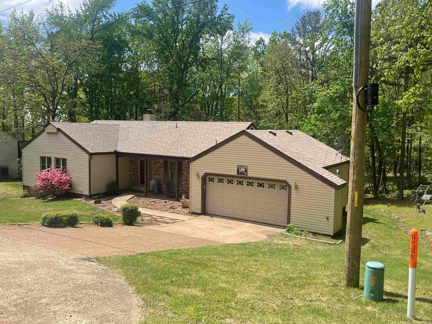 This Charming house is located conveniently close to the heart of Fairfield Bay's business district.  Snuggled into the trees with only neighbors on one side you will feel like you're living in the country. This home has a double garage and a circle drive for a large family or for entertaining.  The enclosed back porch is also heated and cooled so you can be in the nature year round. The home also has several built in cabinets and shelves.